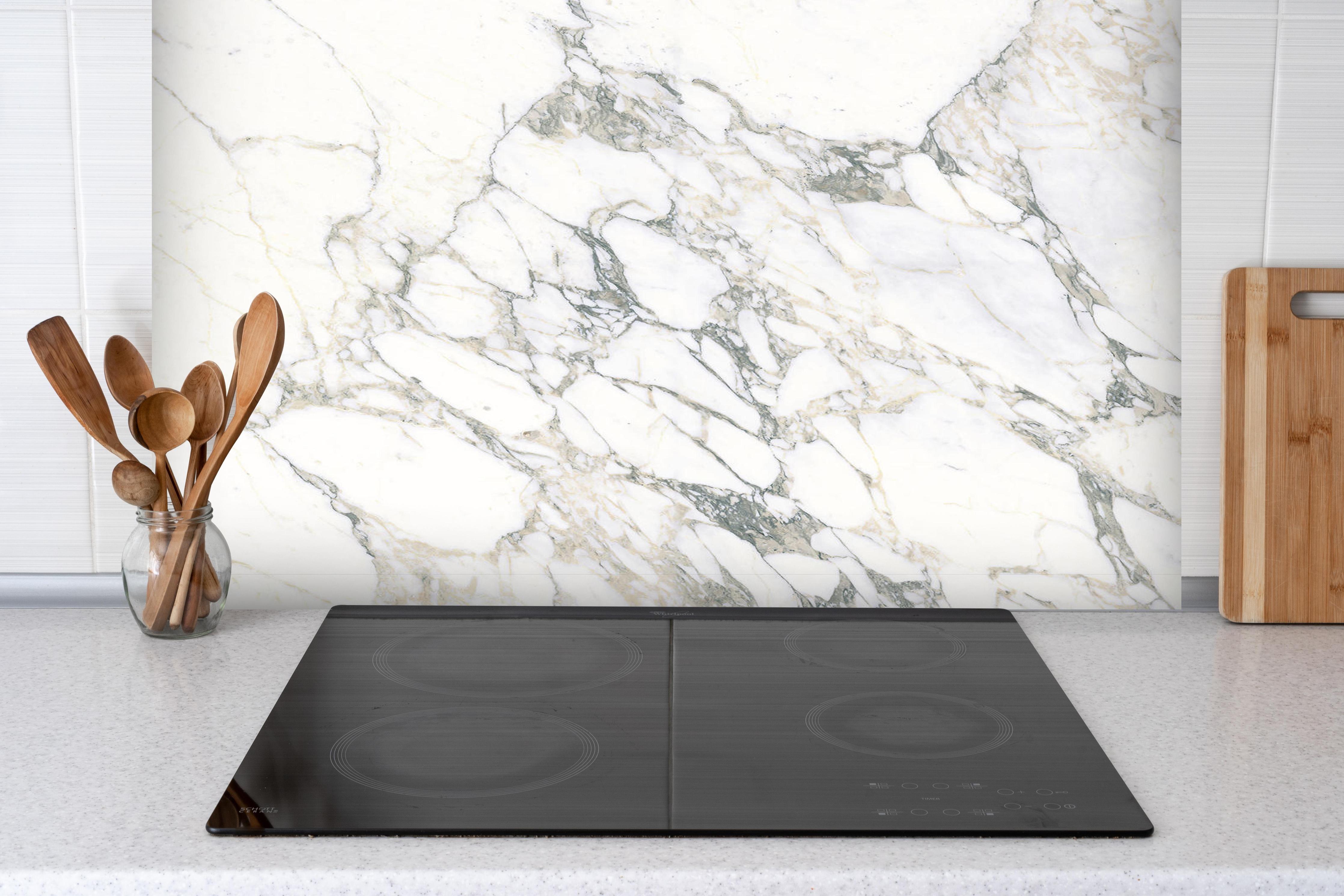 Spritzschutz - Weißer brüchiger Marmor hinter einem Cerankochfeld zwischen Holz-Kochutensilien