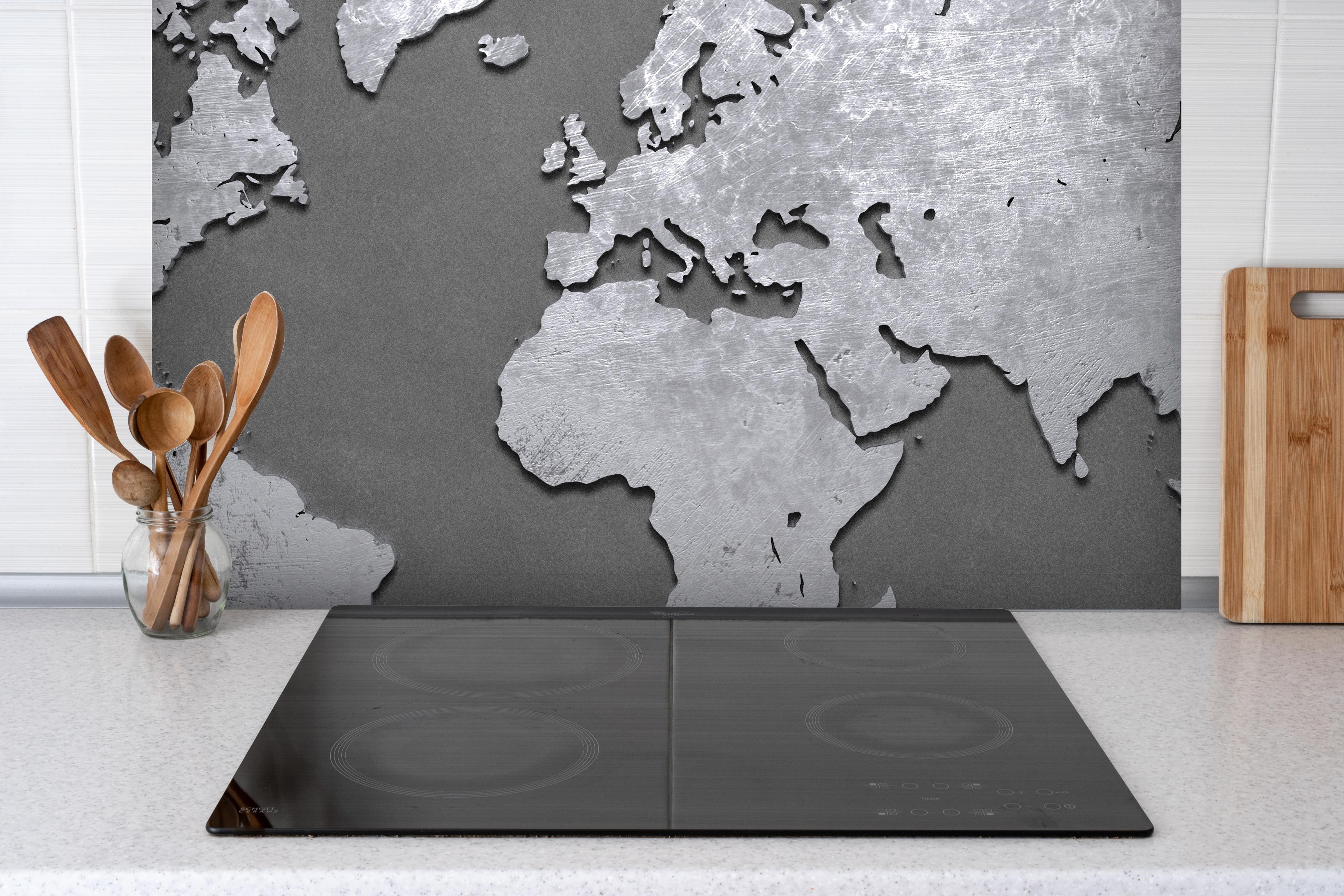 Spritzschutz - Weltkarte aus Metall hinter einem Cerankochfeld zwischen Holz-Kochutensilien