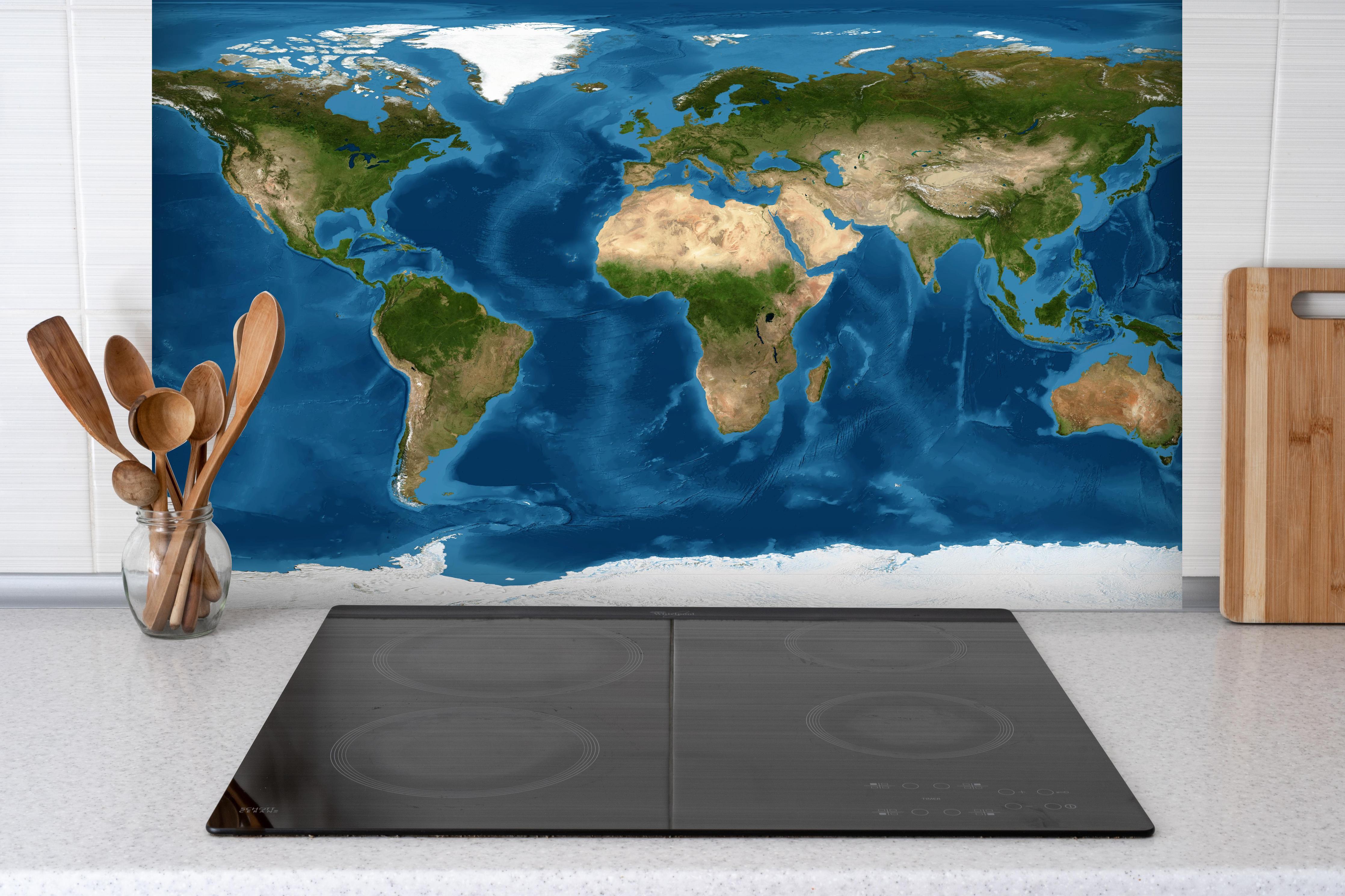 Spritzschutz - Weltkarte farbig hinter einem Cerankochfeld zwischen Holz-Kochutensilien
