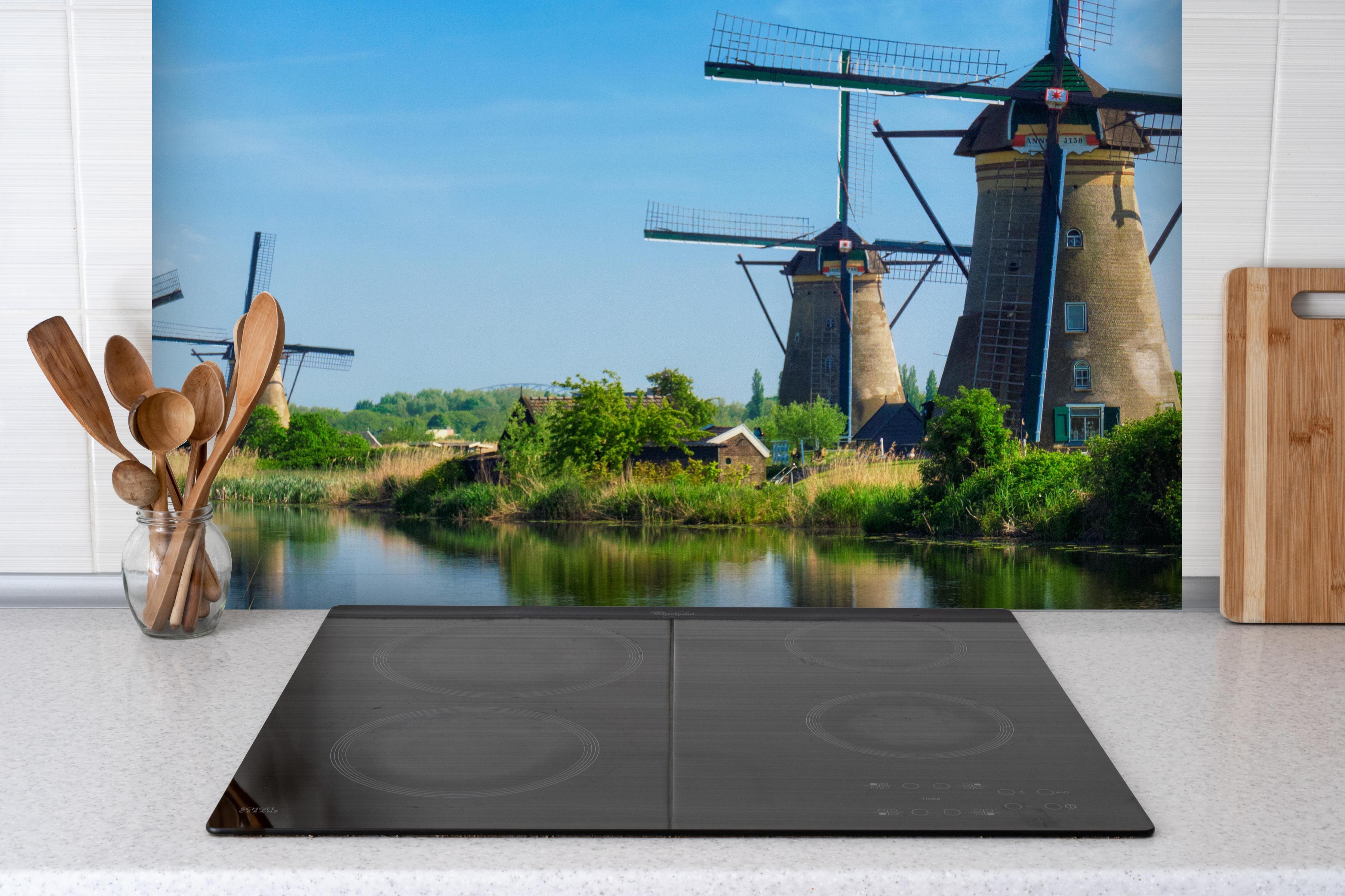 Spritzschutz - Windmühlen in Kinderdijk - Holland hinter einem Cerankochfeld zwischen Holz-Kochutensilien