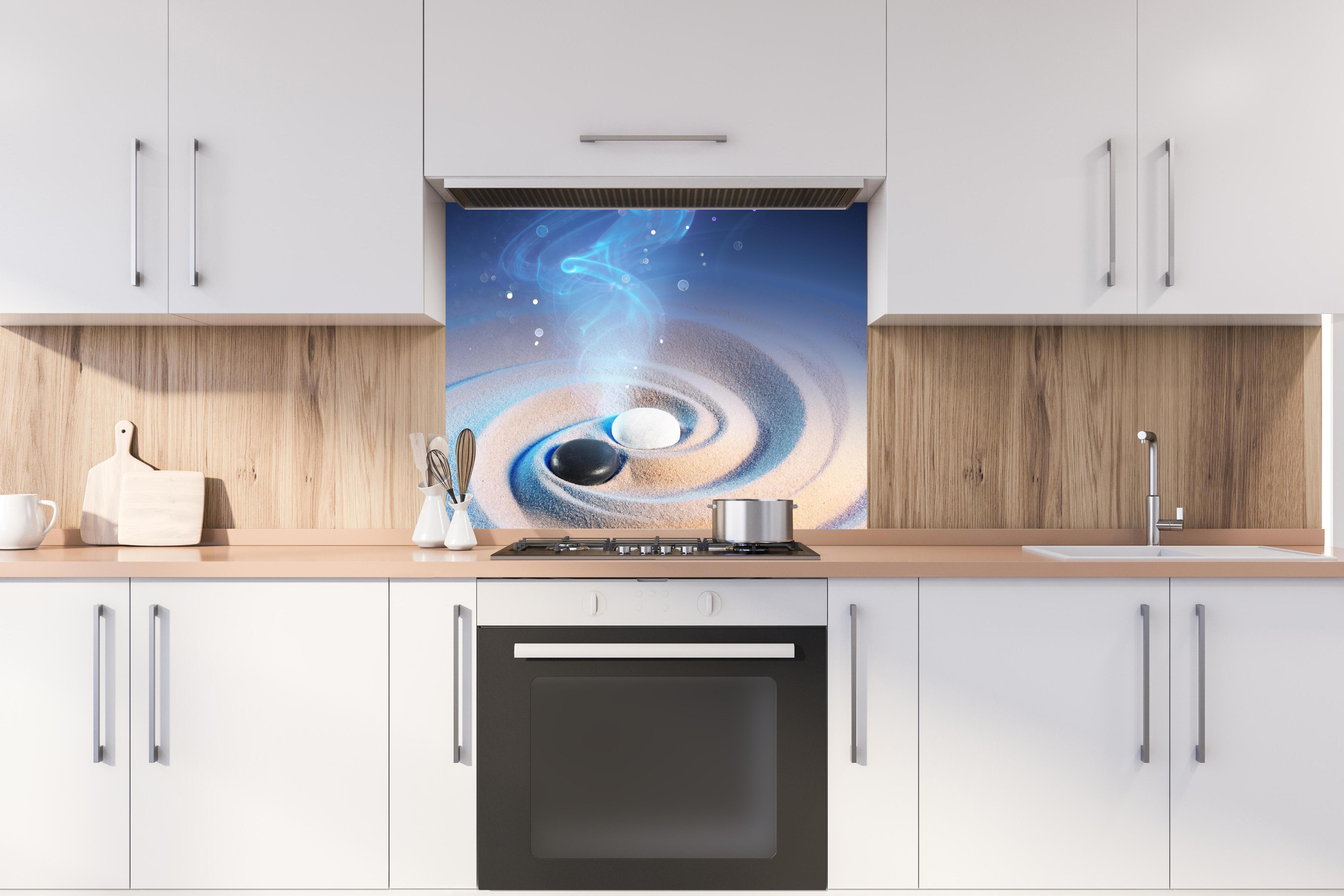 Spritzschutz - Yin und Yang Steine im Sand hinter stilvollem Gasherd unter Dunstabzugshaube
