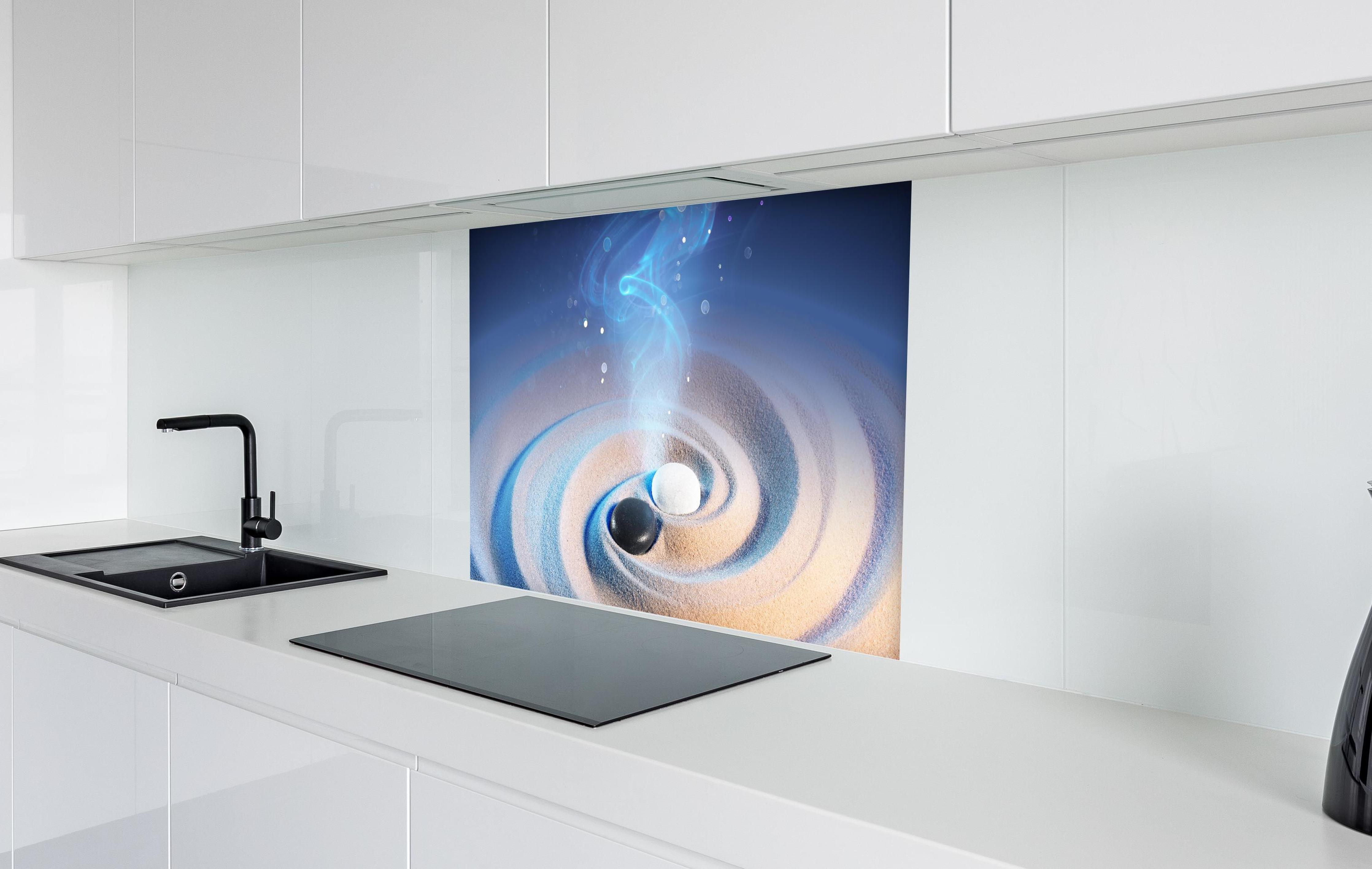 Spritzschutz - Yin und Yang Steine im Sand in weißer Hochglanz-Küche hinter einem Cerankochfeld