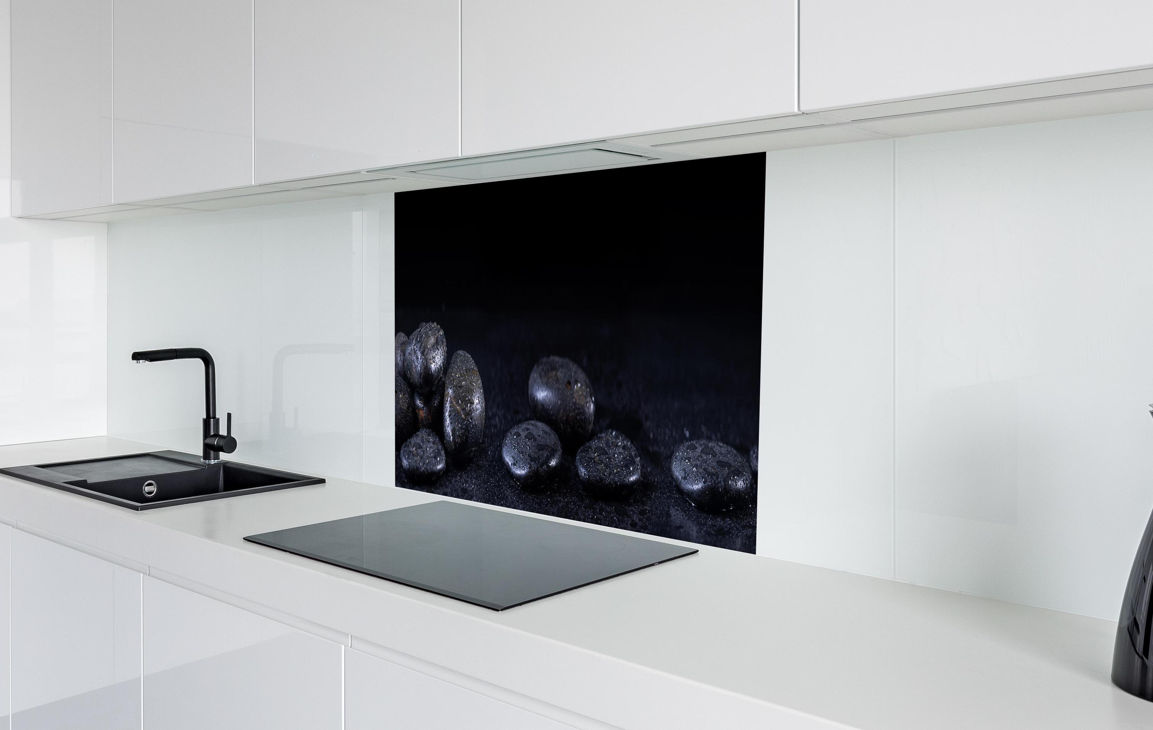 Spritzschutz - Zen - Schwarze Steine in weißer Hochglanz-Küche hinter einem Cerankochfeld