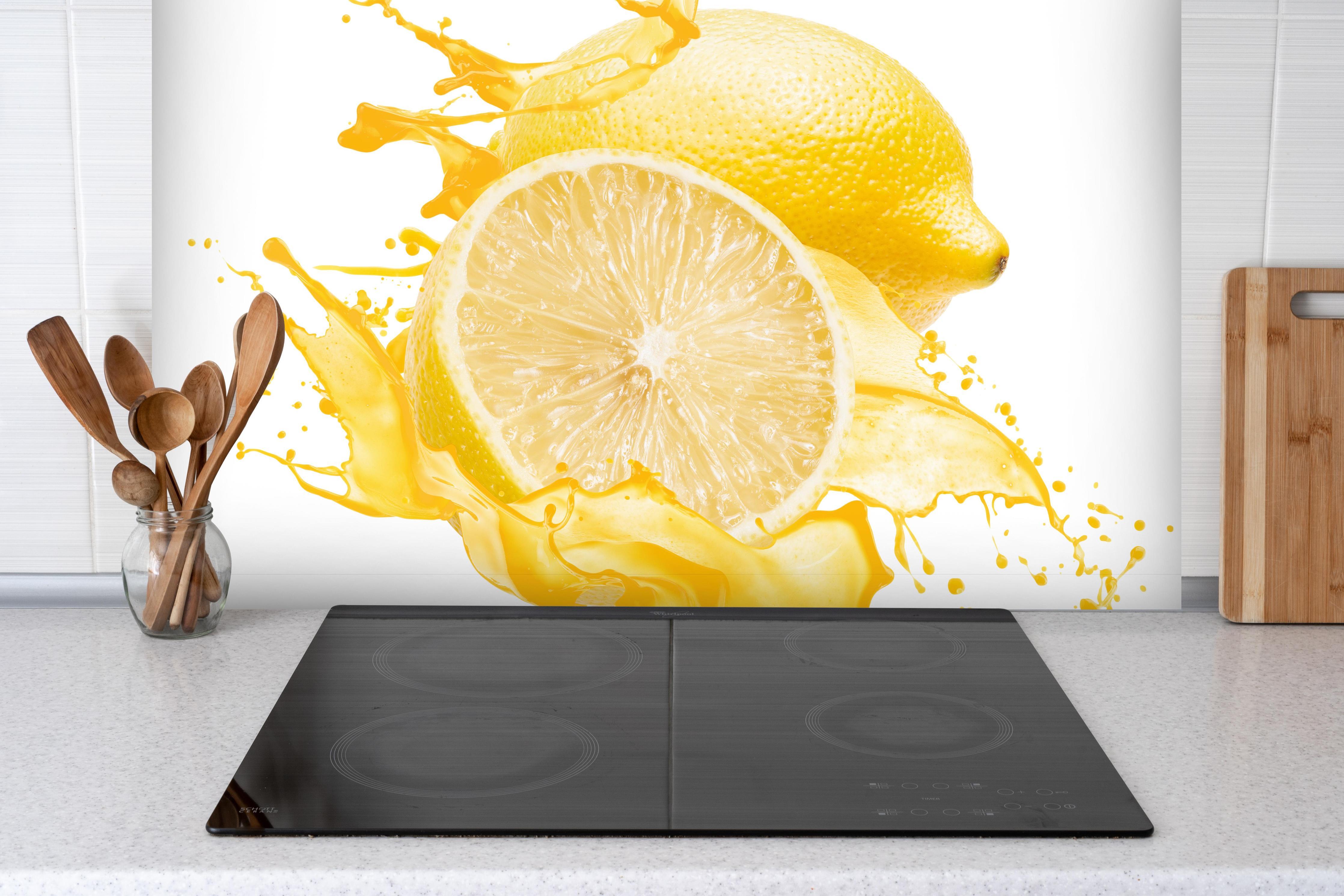 Spritzschutz - Zitronen in gelbem Saft hinter einem Cerankochfeld zwischen Holz-Kochutensilien