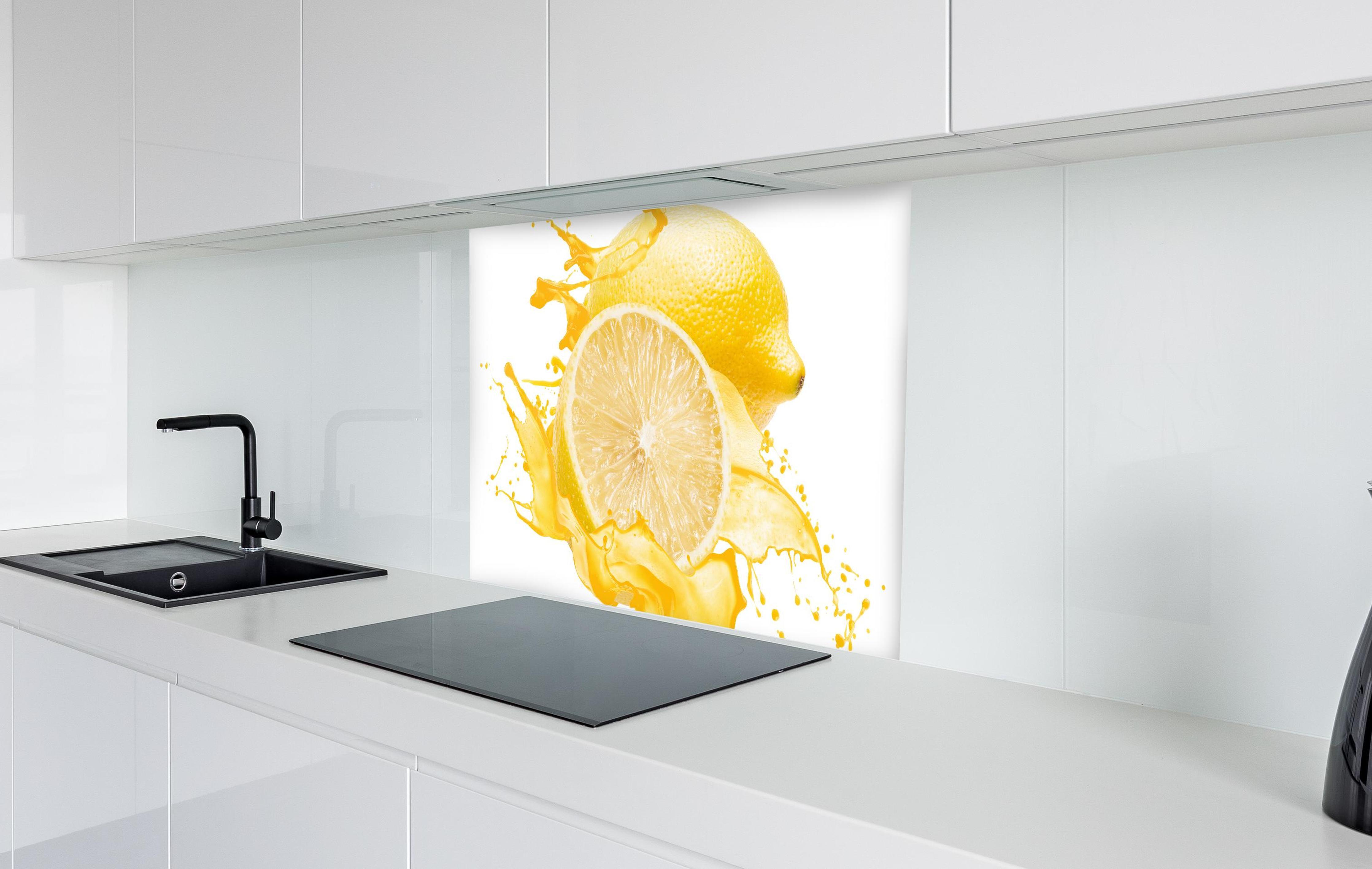 Spritzschutz - Zitronen in gelbem Saft in weißer Hochglanz-Küche hinter einem Cerankochfeld