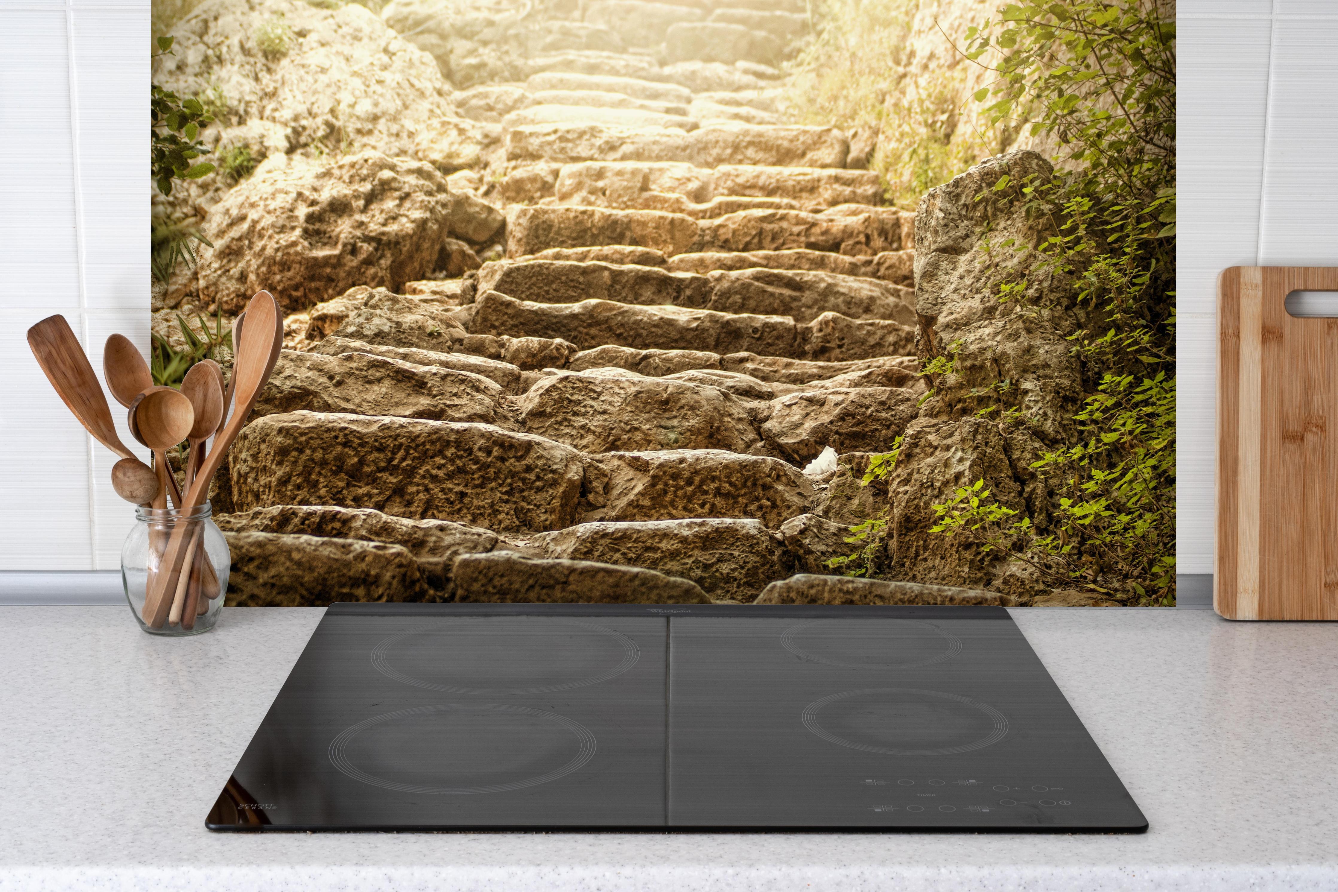 Spritzschutz - bewachsene Steintreppen in der Natur hinter einem Cerankochfeld zwischen Holz-Kochutensilien