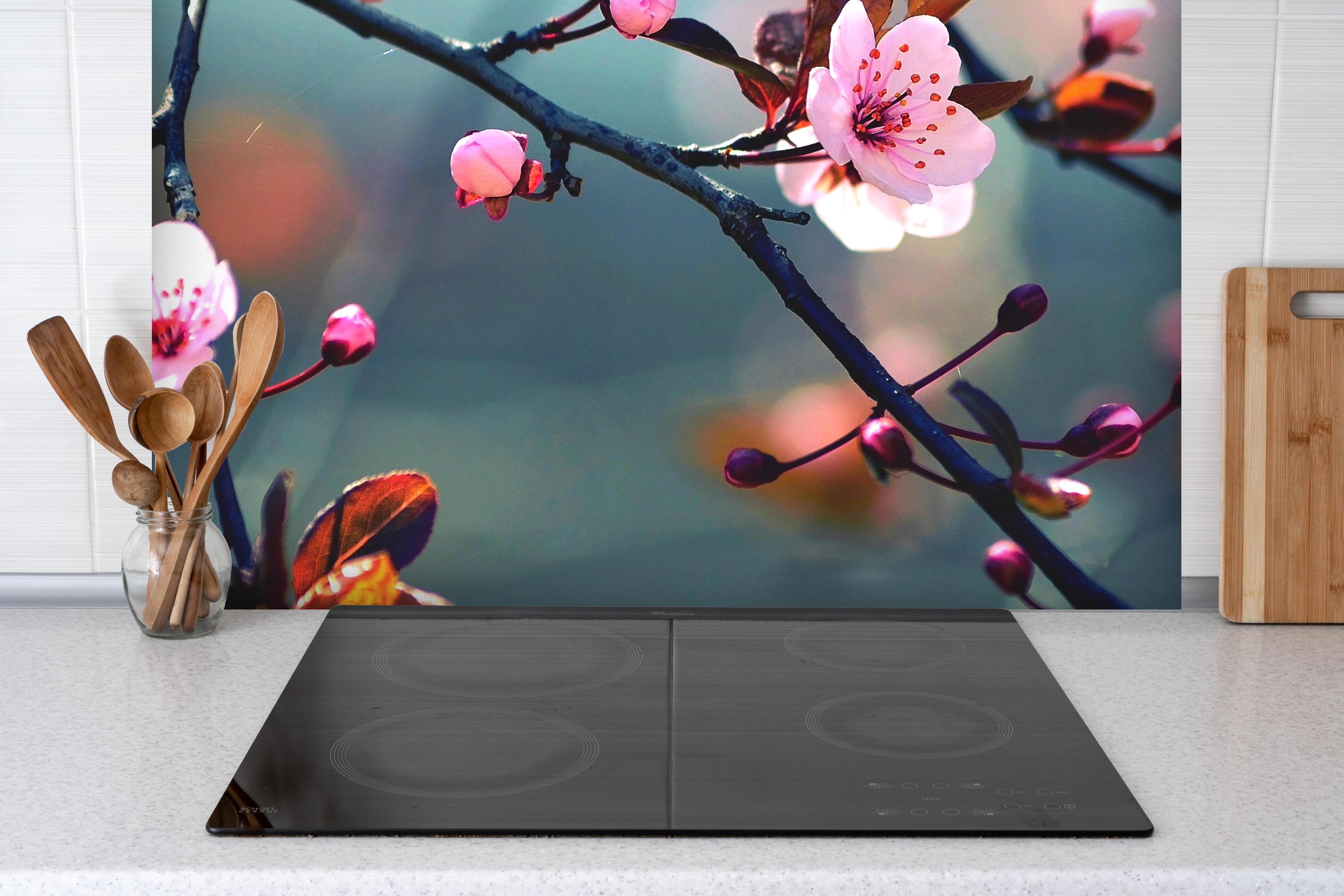 Spritzschutz - blühender japanischer Kirchblütenbaum hinter einem Cerankochfeld zwischen Holz-Kochutensilien