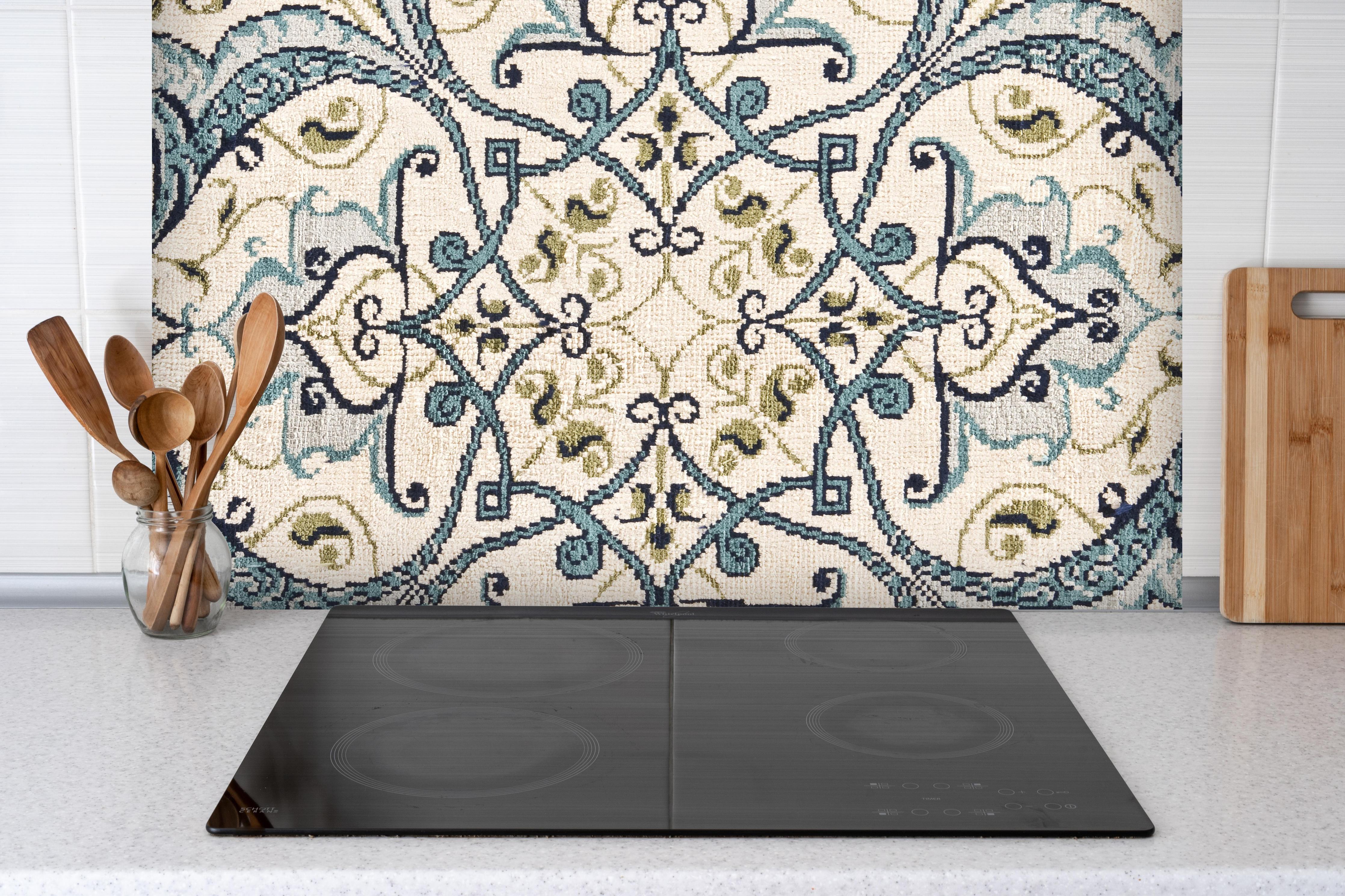Spritzschutz - klassischer Orientalischer Teppich hinter einem Cerankochfeld zwischen Holz-Kochutensilien