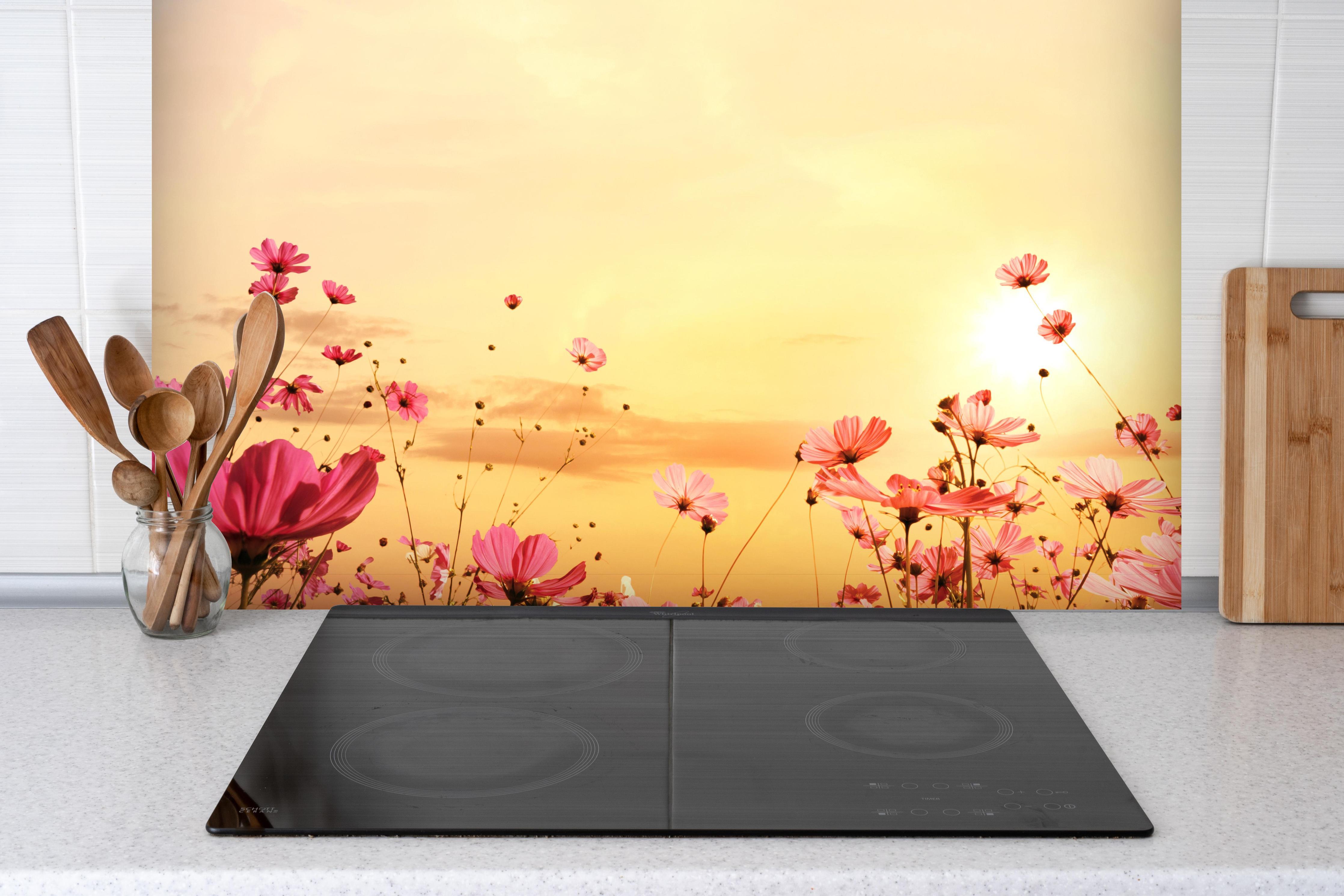 Spritzschutz - rosa Kosmosblumenfeld hinter einem Cerankochfeld zwischen Holz-Kochutensilien