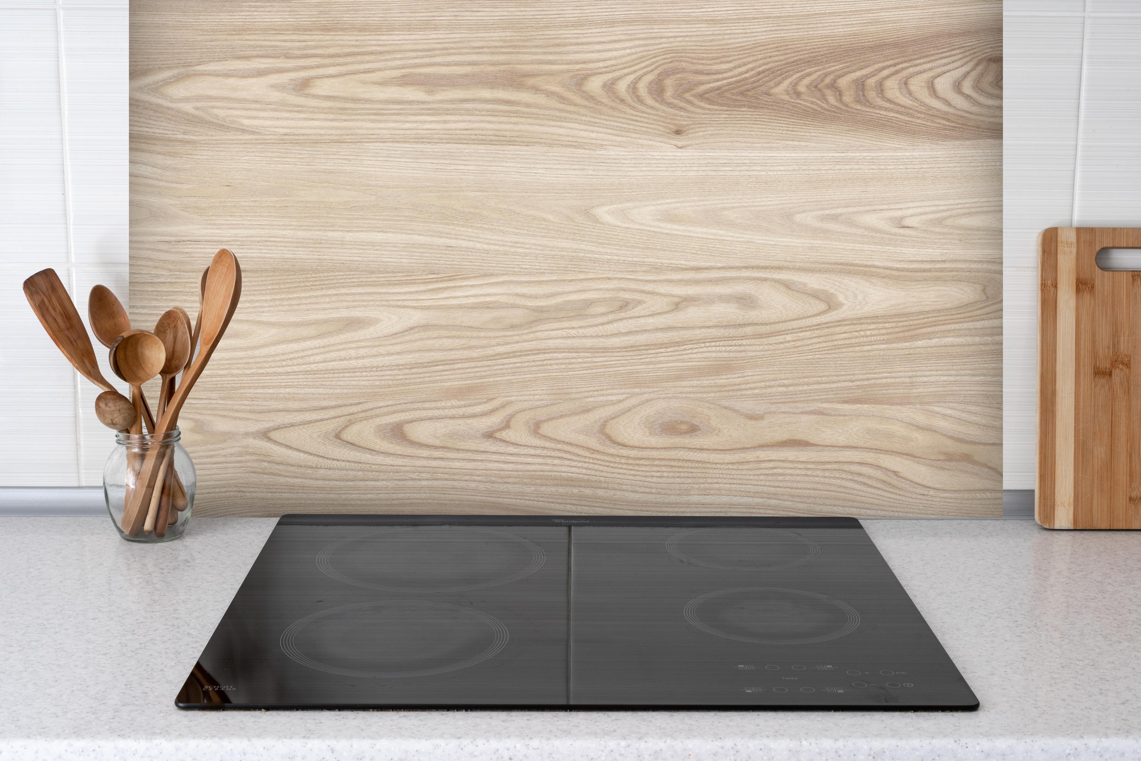 Spritzschutz - schlichtes Holzmuster hinter einem Cerankochfeld zwischen Holz-Kochutensilien