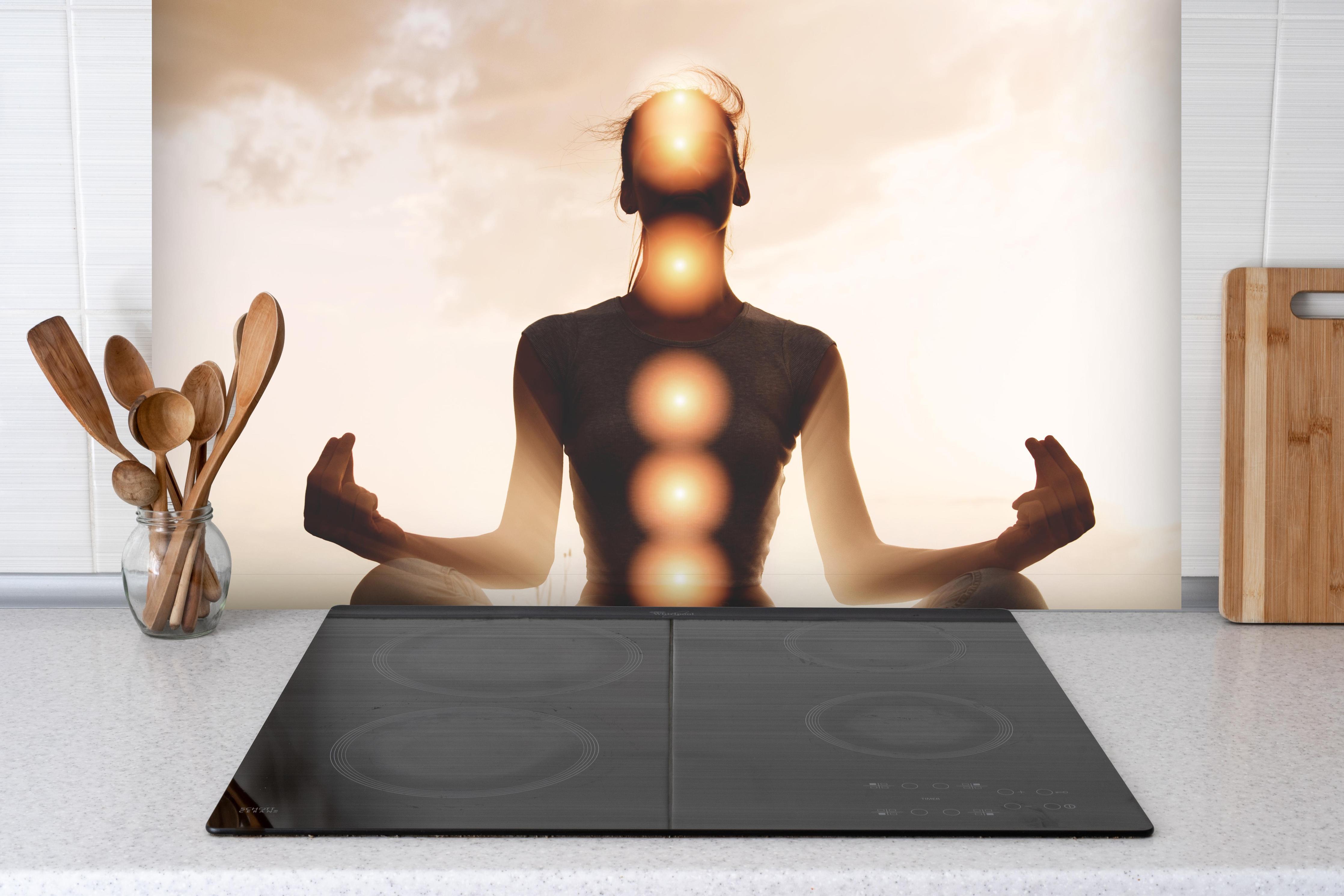 Spritzschutz - spirituelle Energie einer Frau beim Meditieren hinter einem Cerankochfeld zwischen Holz-Kochutensilien