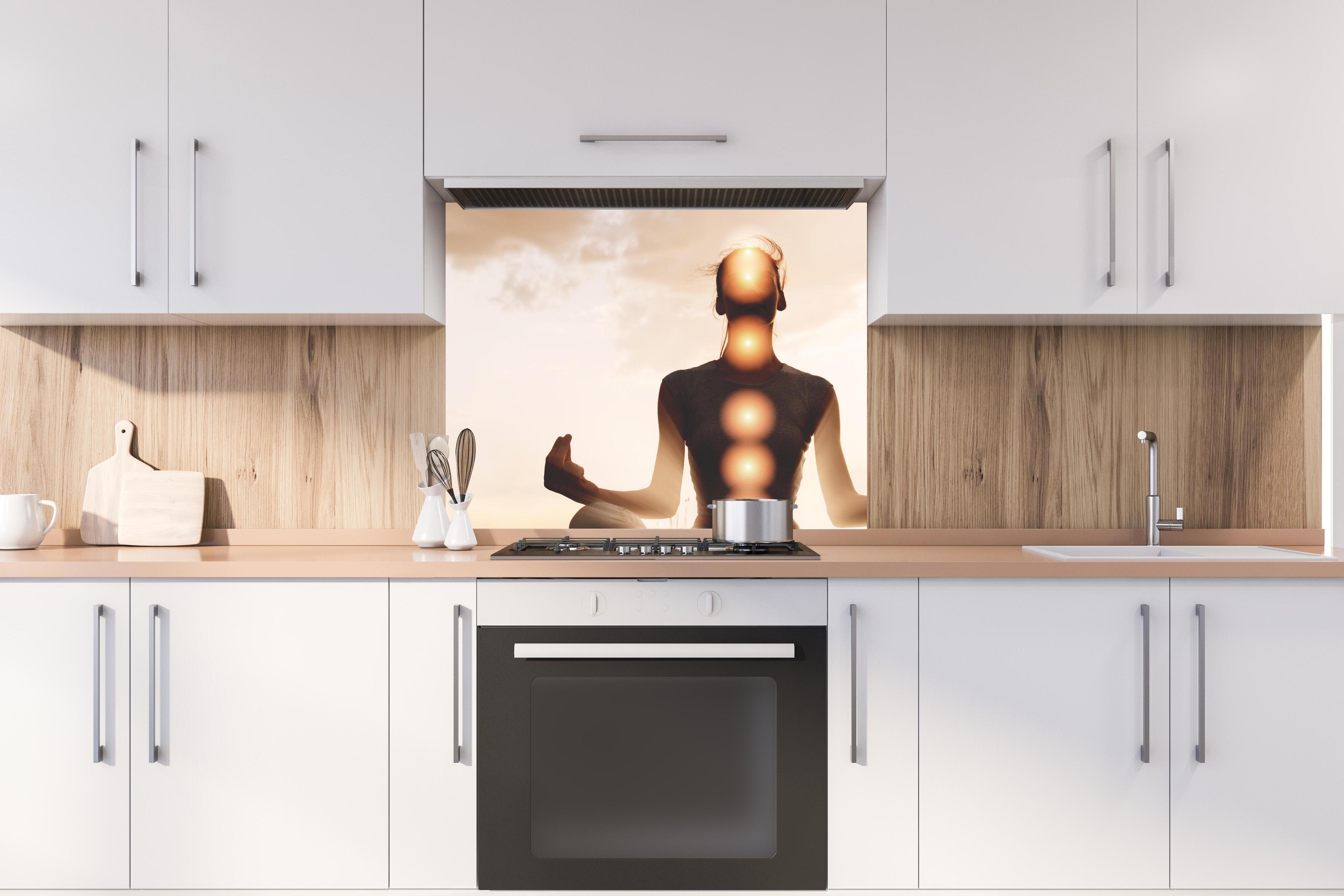Spritzschutz - spirituelle Energie einer Frau beim Meditieren hinter stilvollem Gasherd unter Dunstabzugshaube