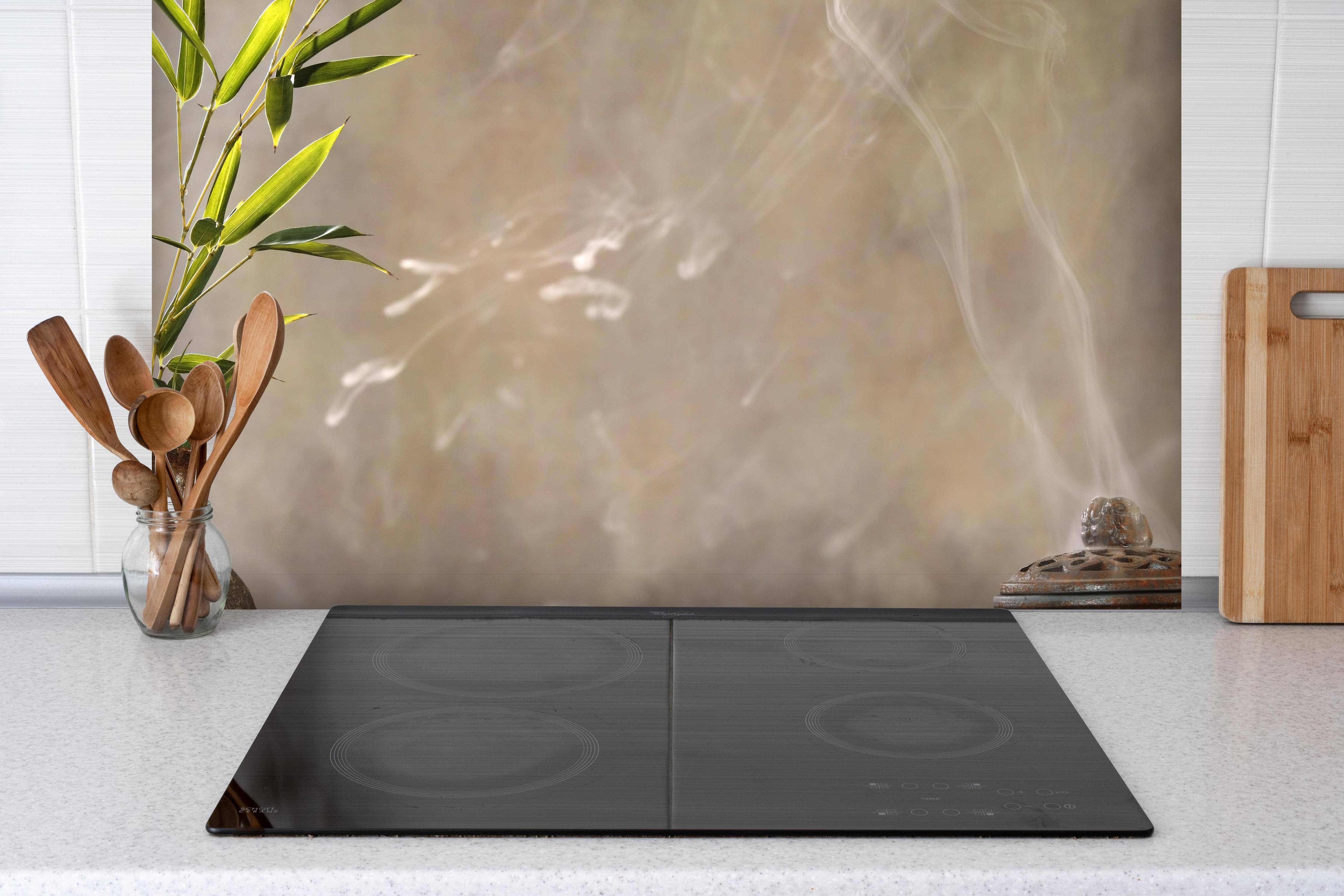 Spritzschutz - spirituelles Spa-Stillleben hinter einem Cerankochfeld zwischen Holz-Kochutensilien