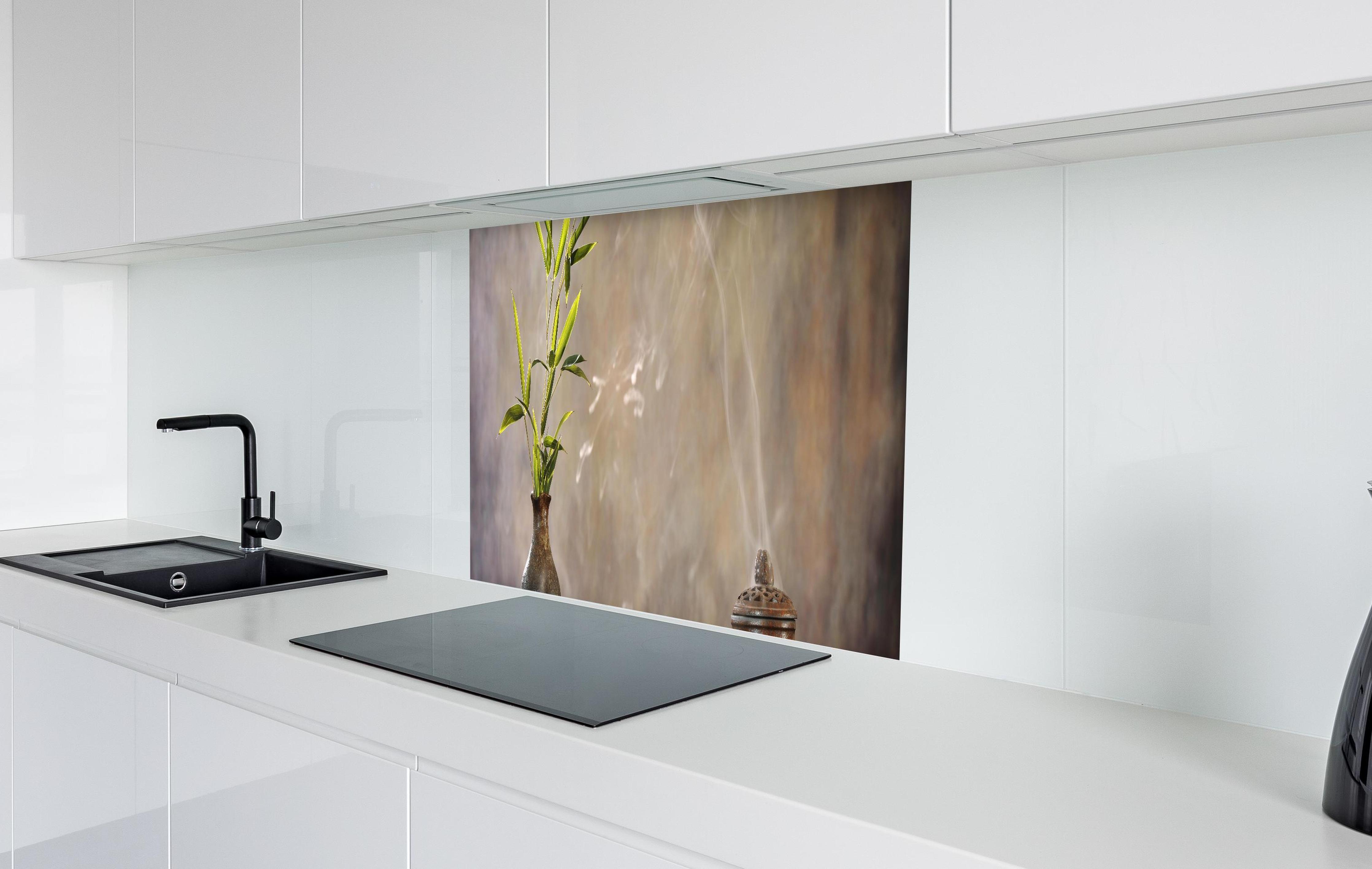 Spritzschutz - spirituelles Spa-Stillleben in weißer Hochglanz-Küche hinter einem Cerankochfeld
