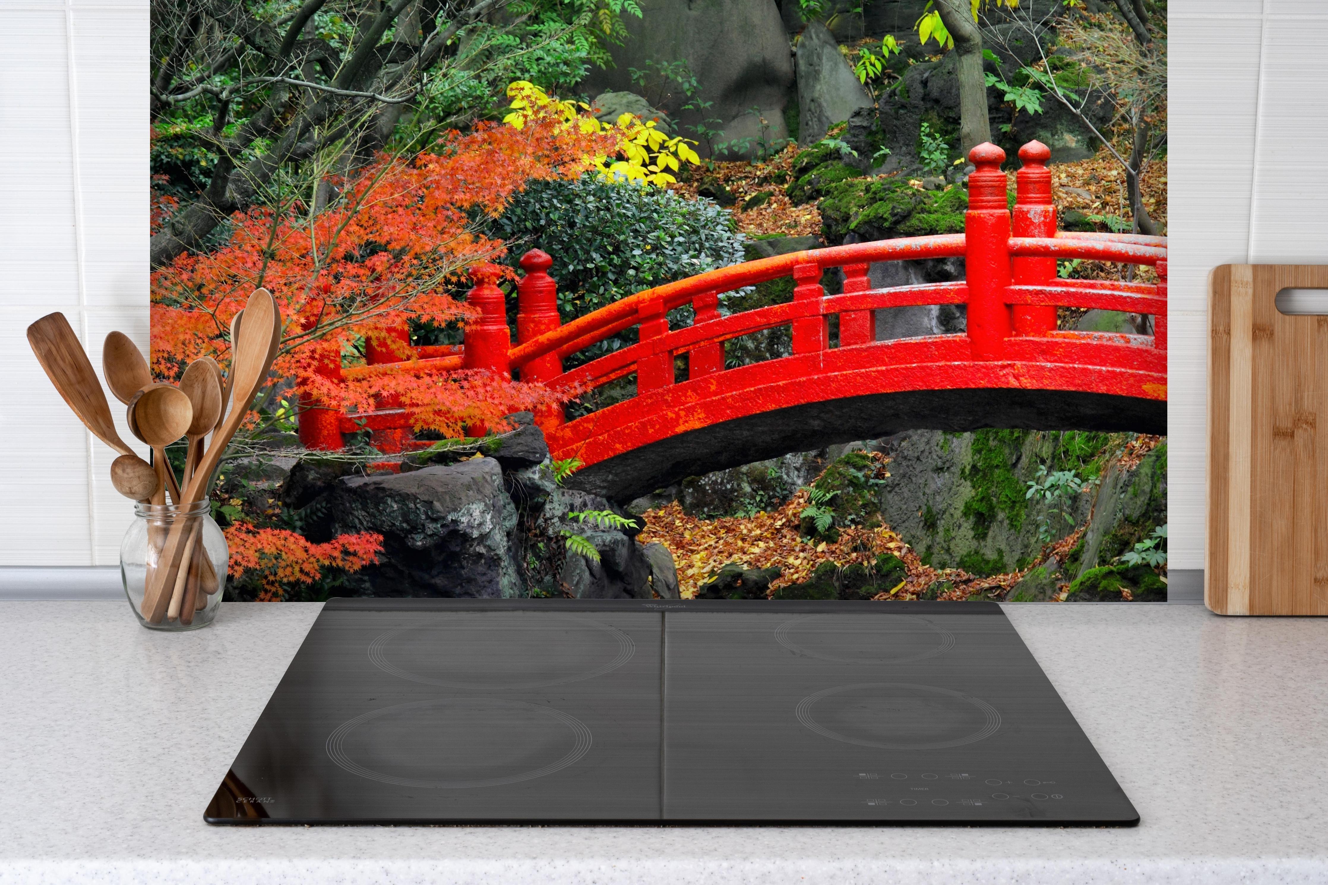 Spritzschutz - traditioneller japanischer Garten an Teich hinter einem Cerankochfeld zwischen Holz-Kochutensilien