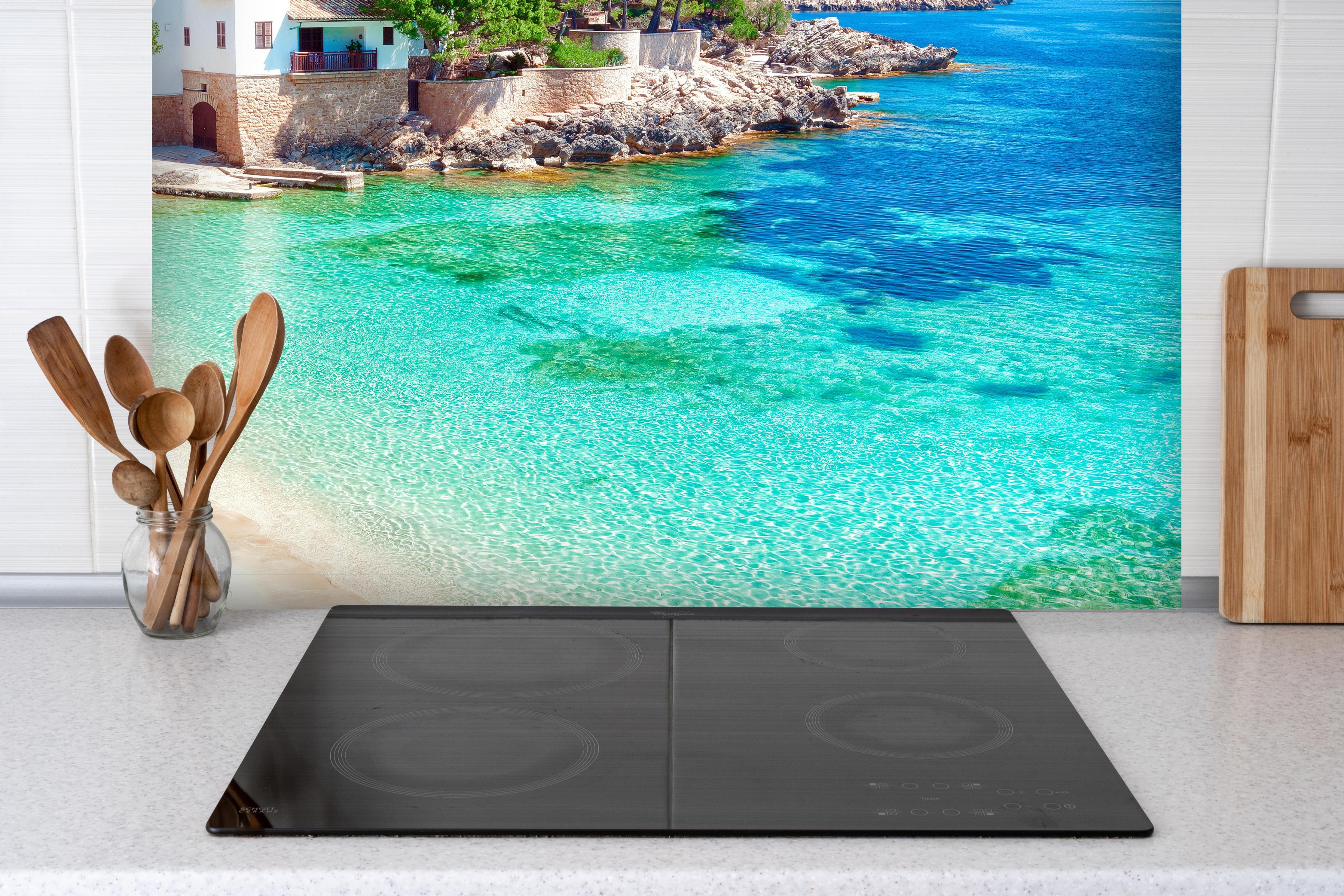 Spritzschutz - traumhafter Mallorca Strand hinter einem Cerankochfeld zwischen Holz-Kochutensilien
