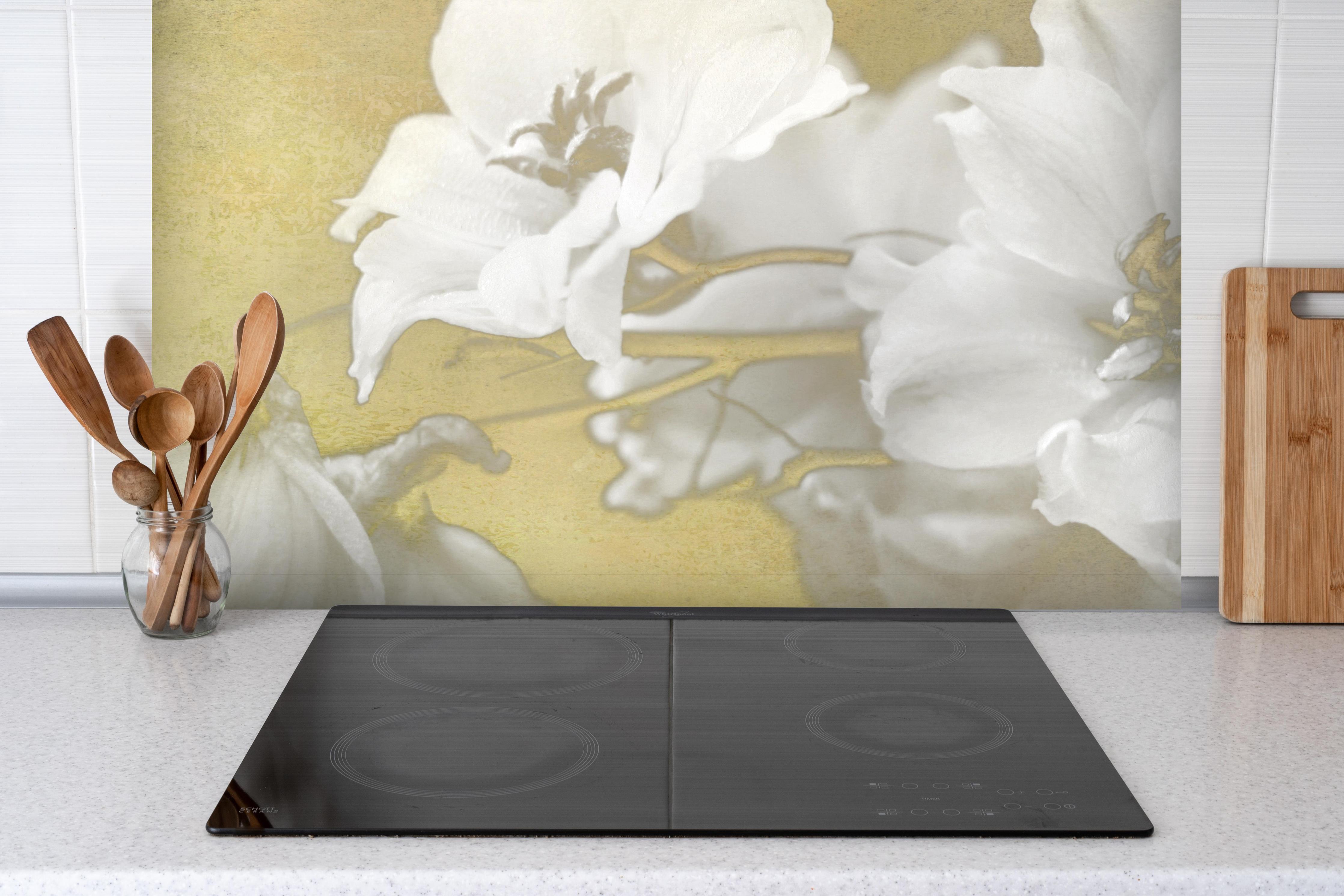 Spritzschutz - weiße Blumen auf goldenem Hintergrund hinter einem Cerankochfeld zwischen Holz-Kochutensilien