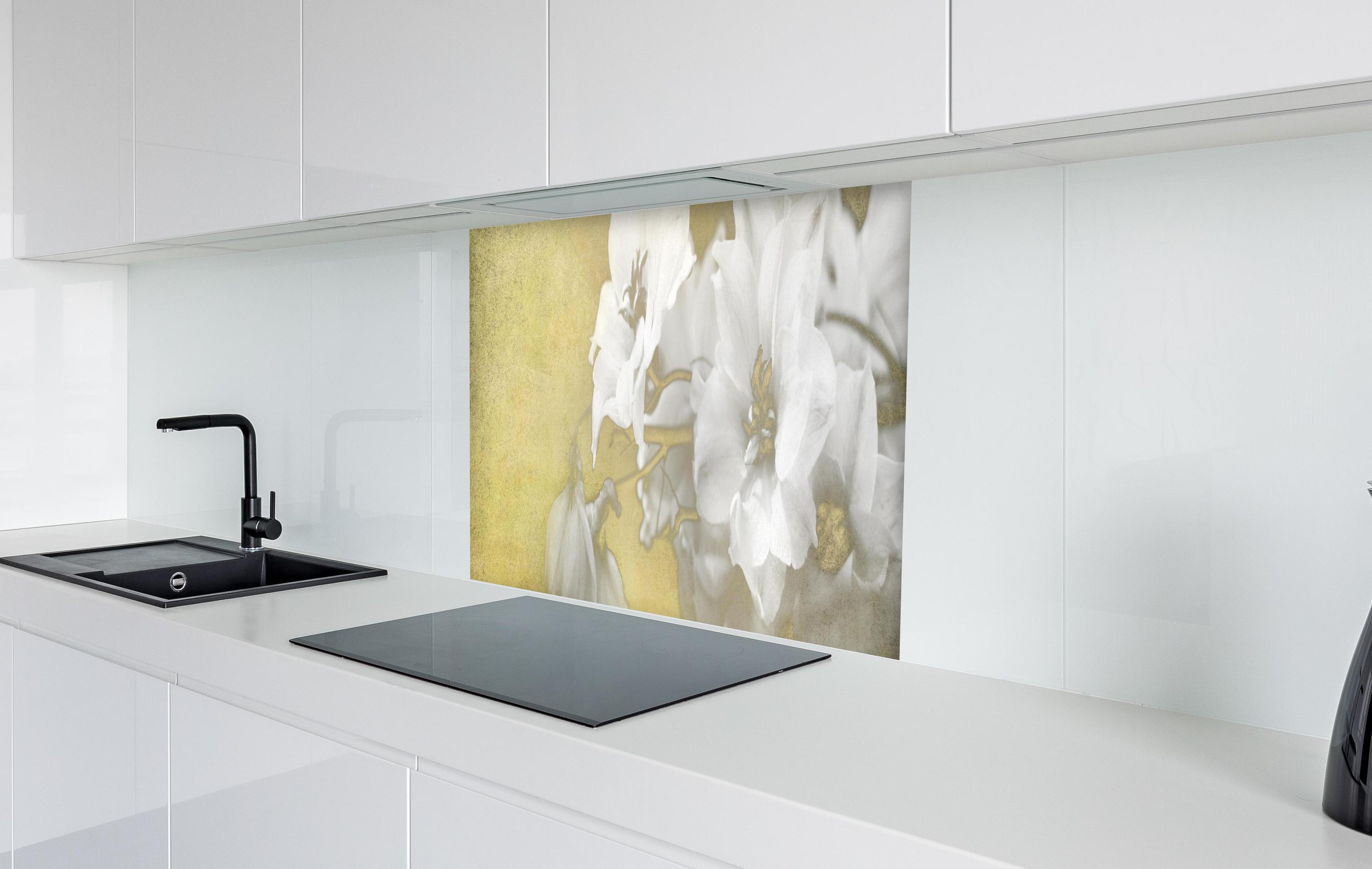 Spritzschutz - weiße Blumen auf goldenem Hintergrund in weißer Hochglanz-Küche hinter einem Cerankochfeld