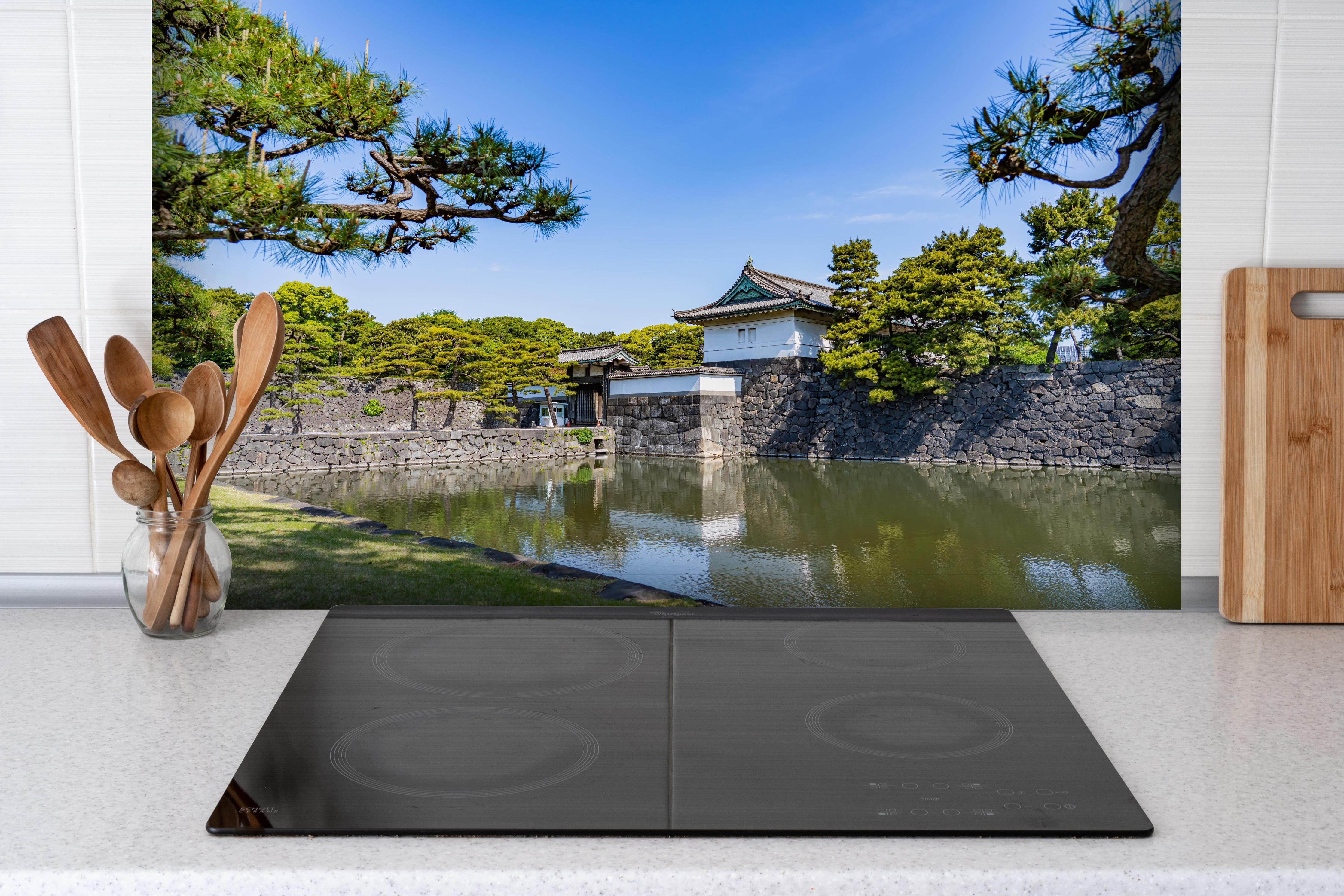Spritzschutz - Stadtlandschaft von Tokio hinter einem Cerankochfeld zwischen Holz-Kochutensilien