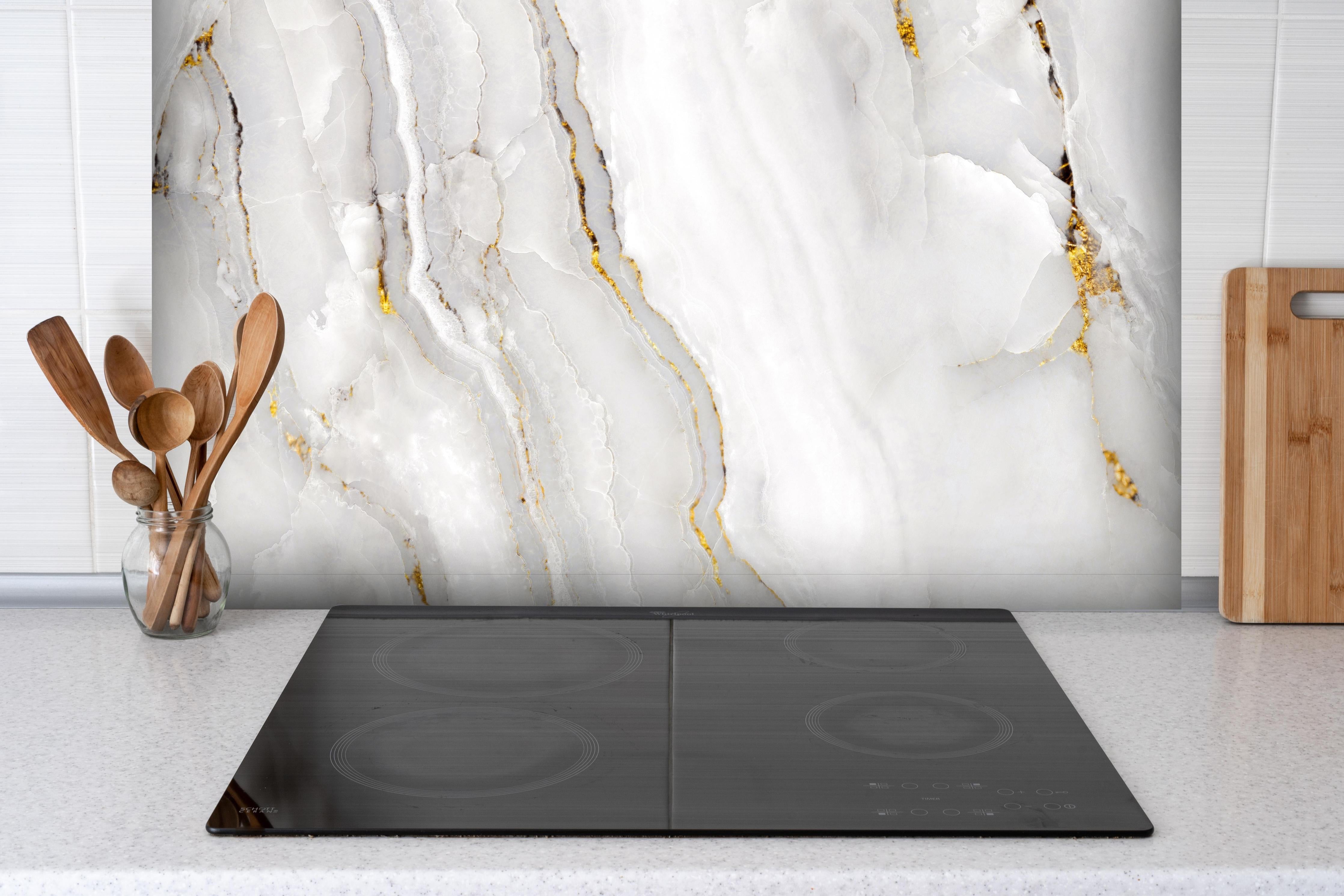 Spritzschutz - Statuario Marmor mit goldenen Akzenten hinter einem Cerankochfeld zwischen Holz-Kochutensilien