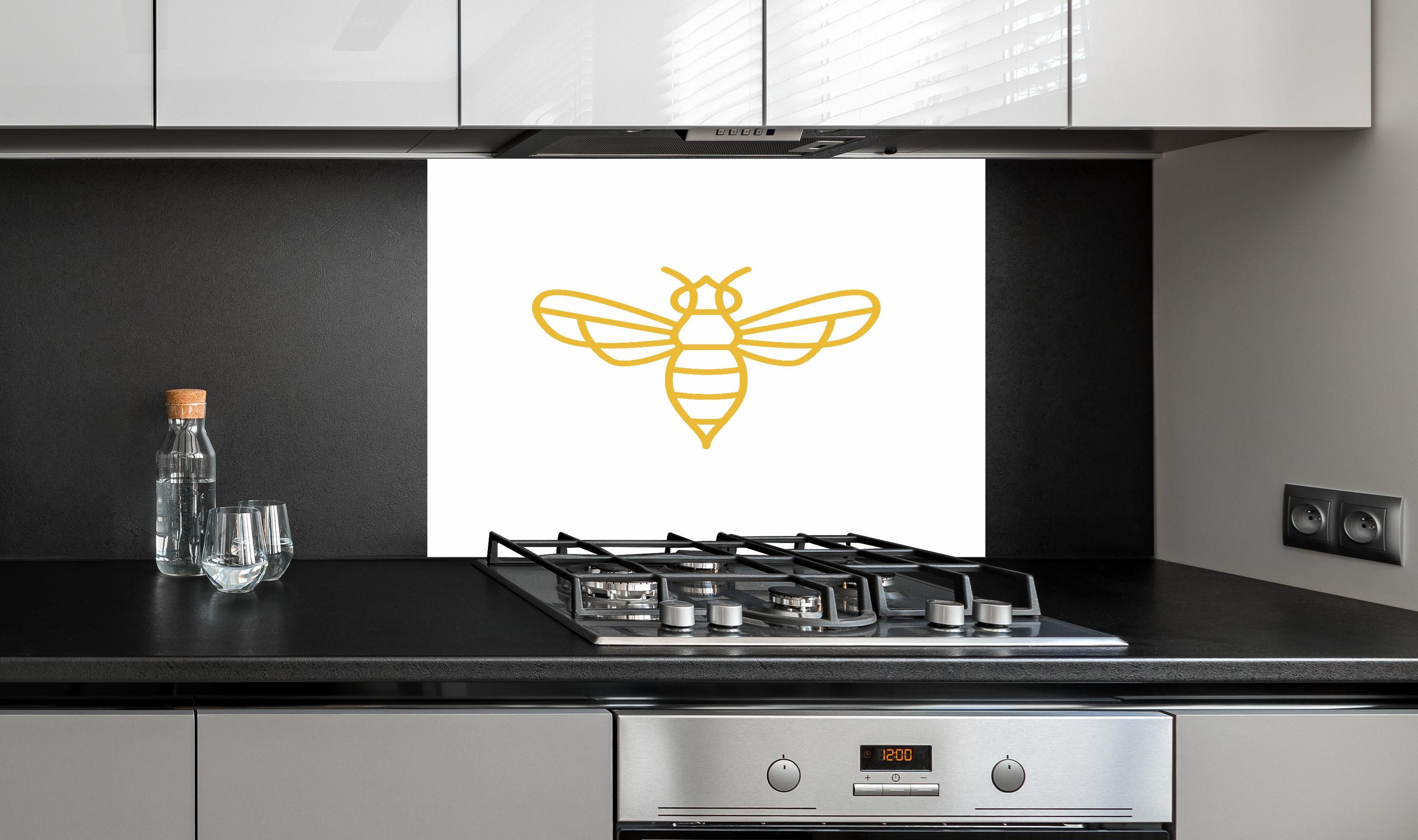 Spritzschutz - Stilisierte Goldfarbene Biene Illustration hinter einem Cerankochfeld zwischen Holz-Kochutensilien