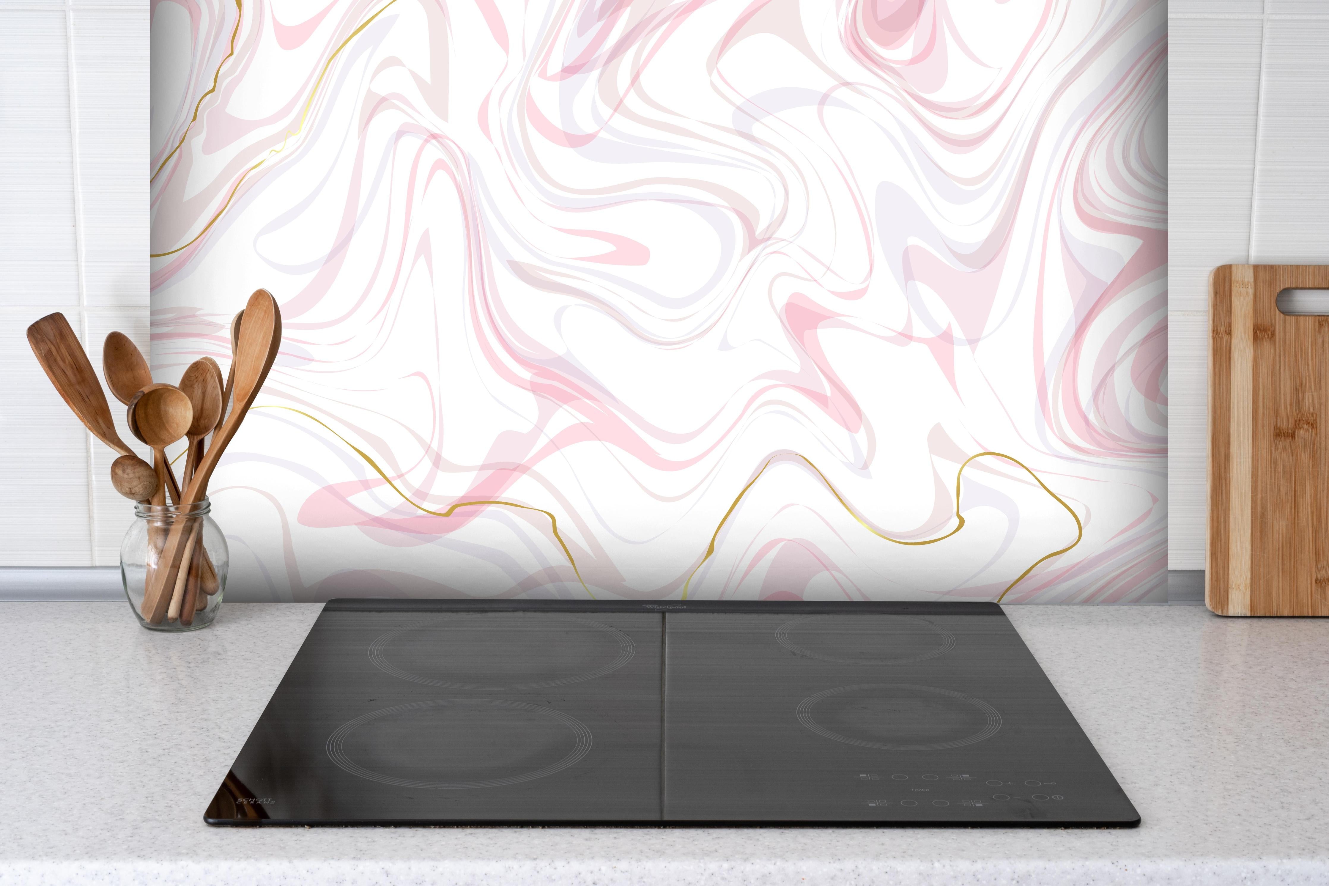 Spritzschutz - Stilvolle Rosé-Weiß Marmorierung mit Goldakzenten hinter einem Cerankochfeld zwischen Holz-Kochutensilien
