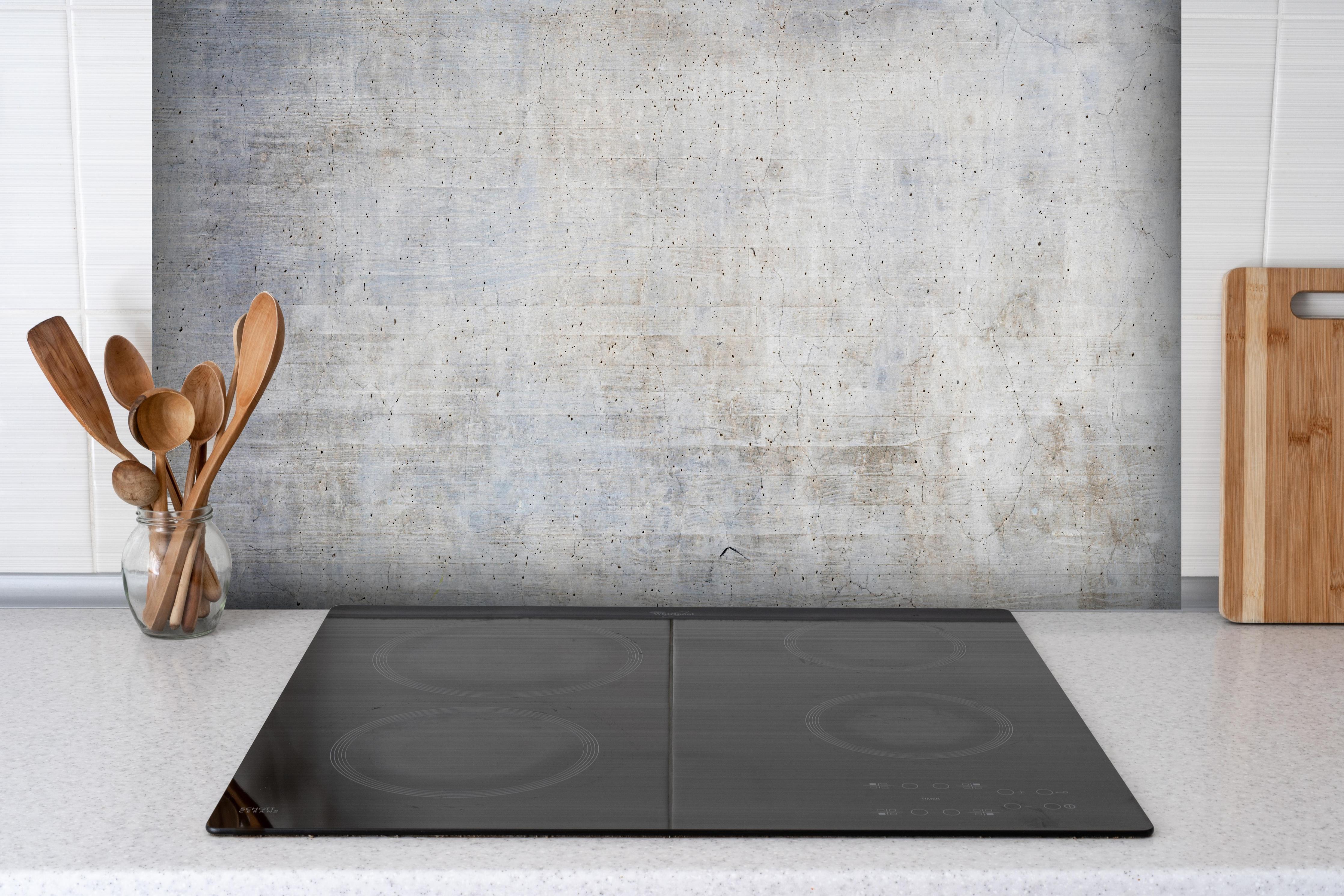 Spritzschutz - Stilvolle grau-weiße Betonwand Textur hinter einem Cerankochfeld zwischen Holz-Kochutensilien