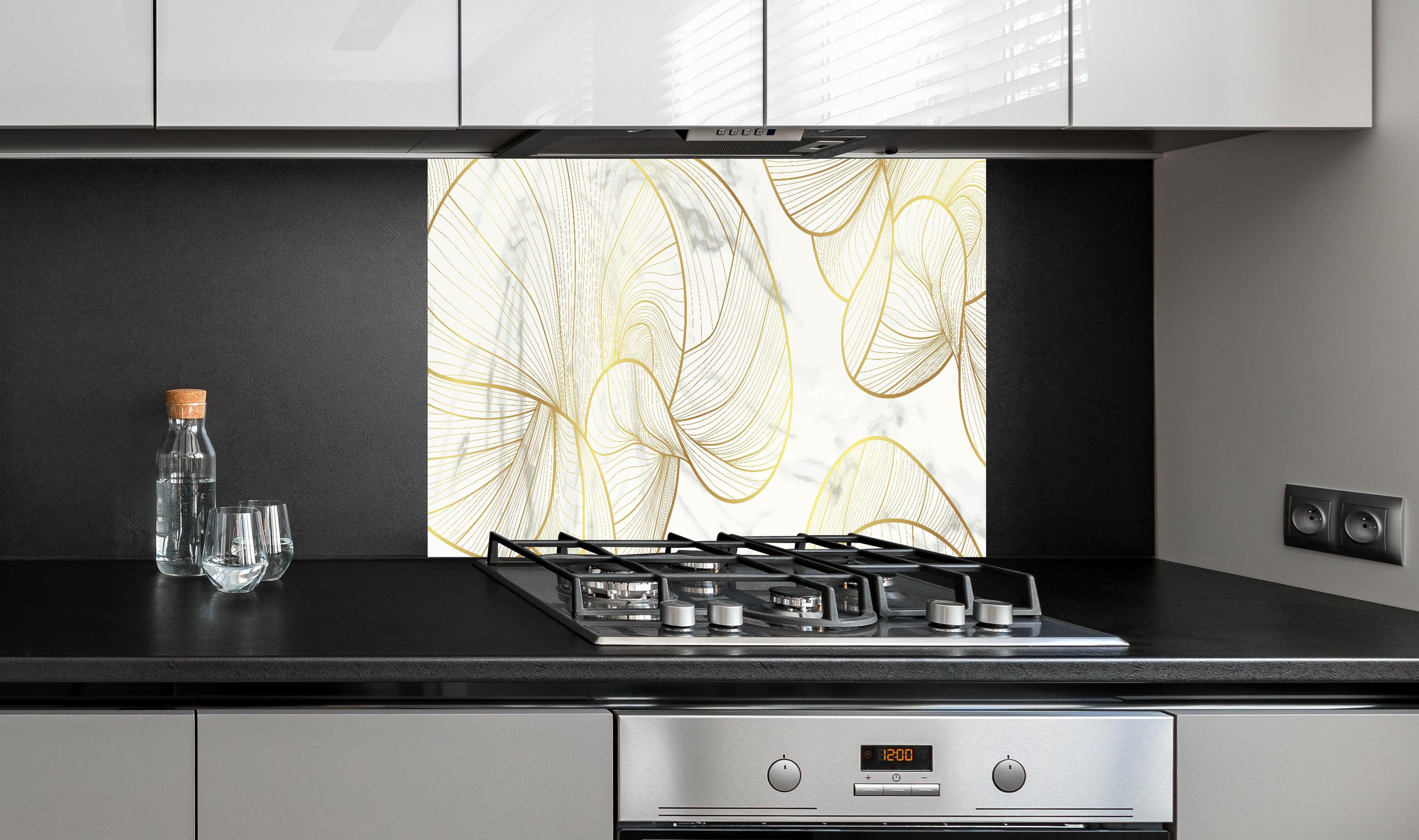 Spritzschutz - Stilvolles Weiß mit goldenem Linienmuster hinter einem Cerankochfeld zwischen Holz-Kochutensilien