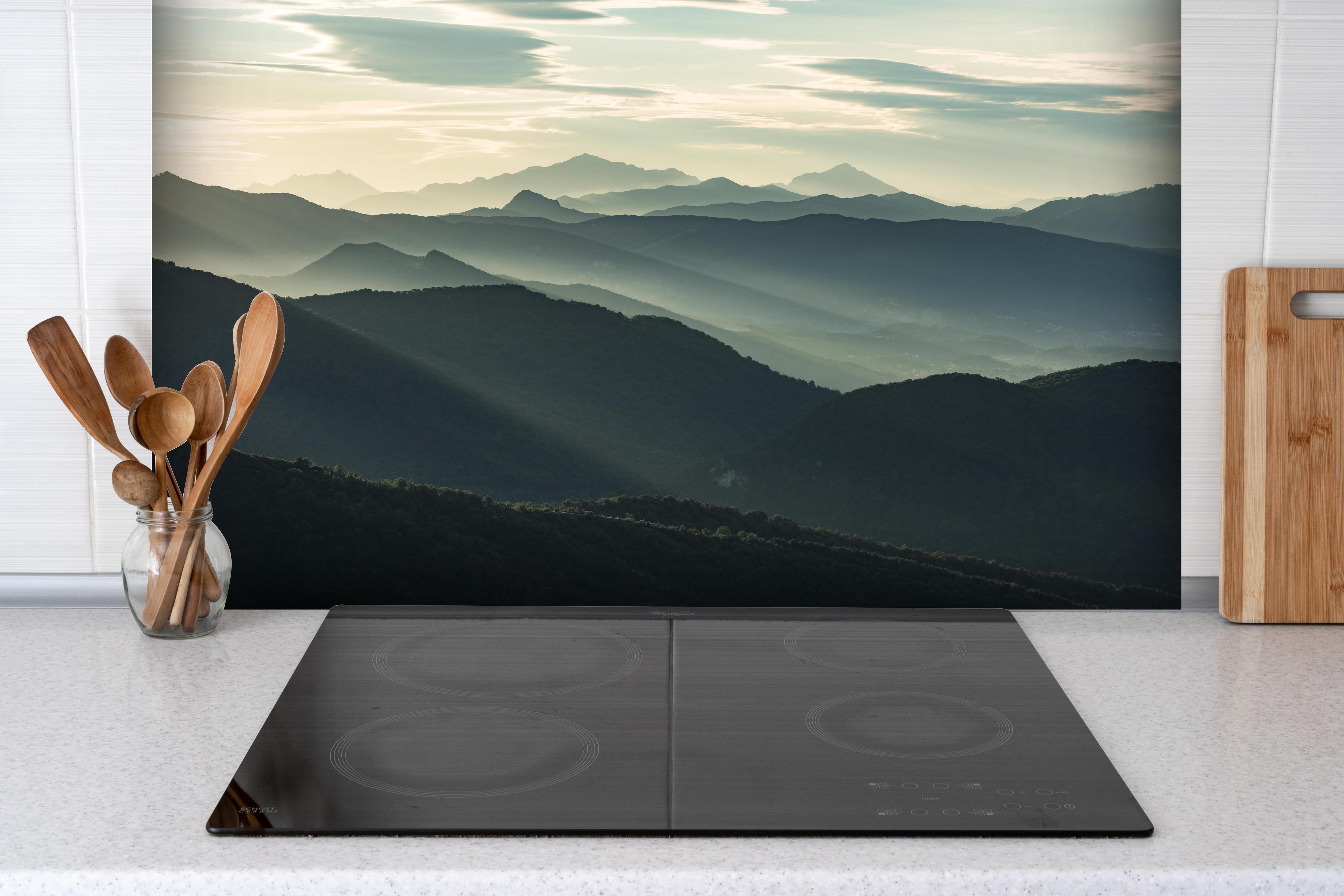 Spritzschutz - Stimmungsvolles Alpenglow bei Morgendämmerung hinter einem Cerankochfeld zwischen Holz-Kochutensilien