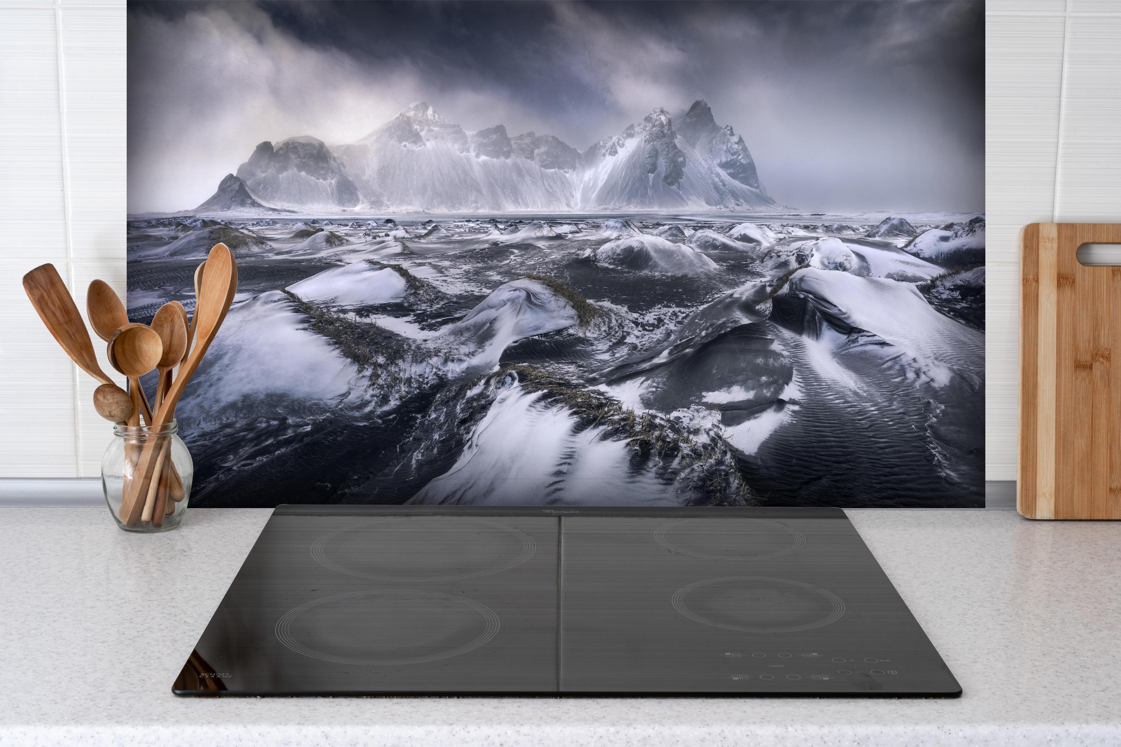 Spritzschutz - Stokksnes Bergkulisse im Schneesturm hinter einem Cerankochfeld zwischen Holz-Kochutensilien