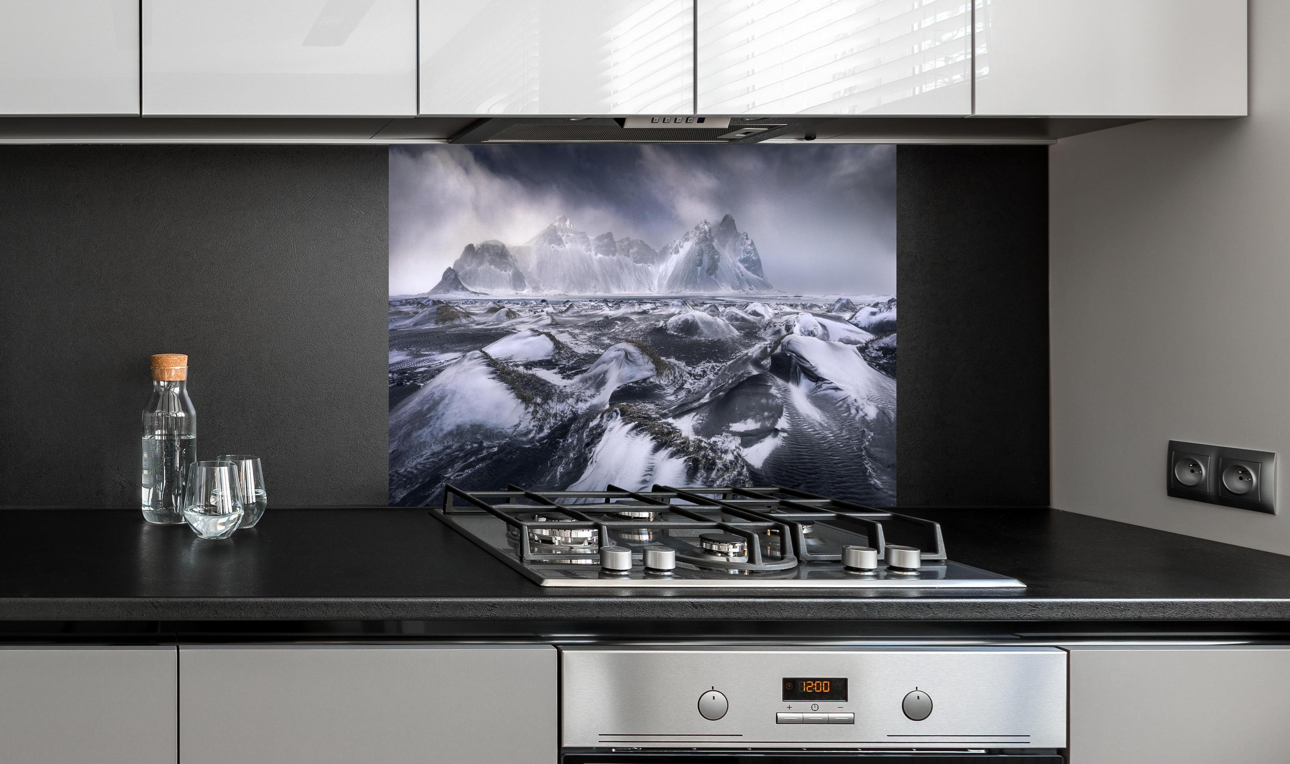 Spritzschutz - Stokksnes Bergkulisse im Schneesturm hinter einem Cerankochfeld zwischen Holz-Kochutensilien