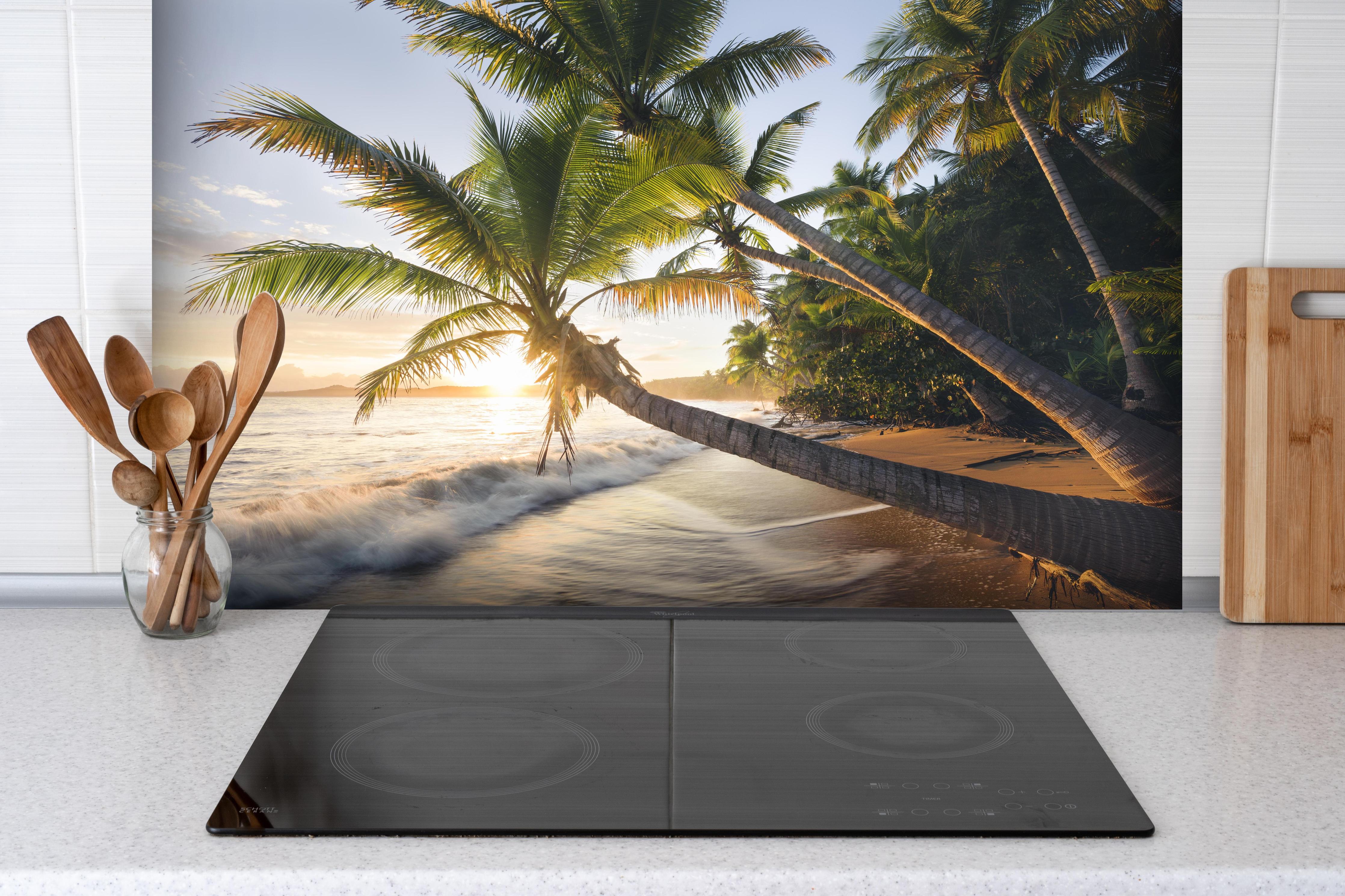 Spritzschutz - Strand in der Karibik bei Sonnenuntergang hinter einem Cerankochfeld zwischen Holz-Kochutensilien