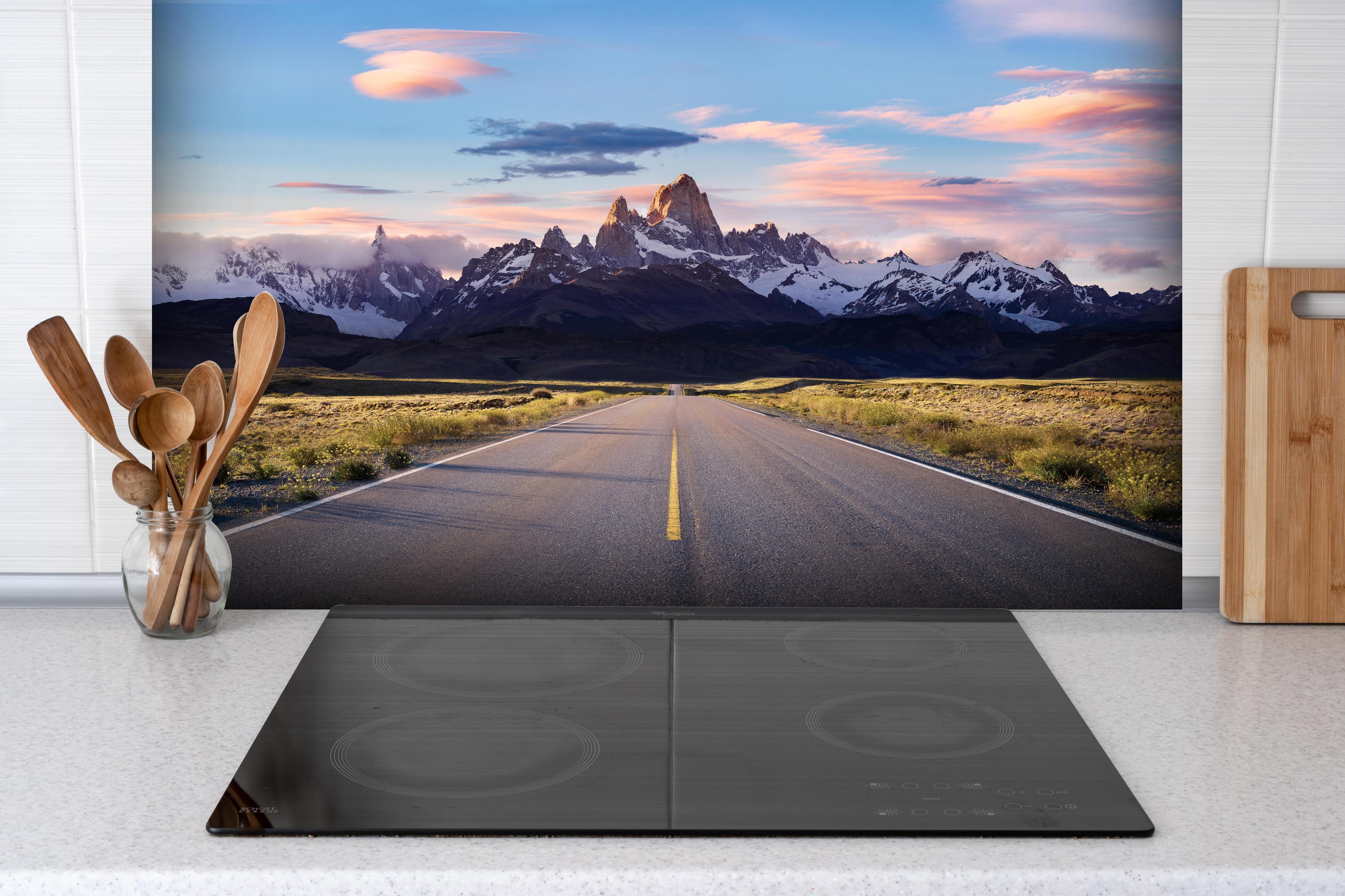 Spritzschutz - Straße mit Blick auf Berge hinter einem Cerankochfeld zwischen Holz-Kochutensilien