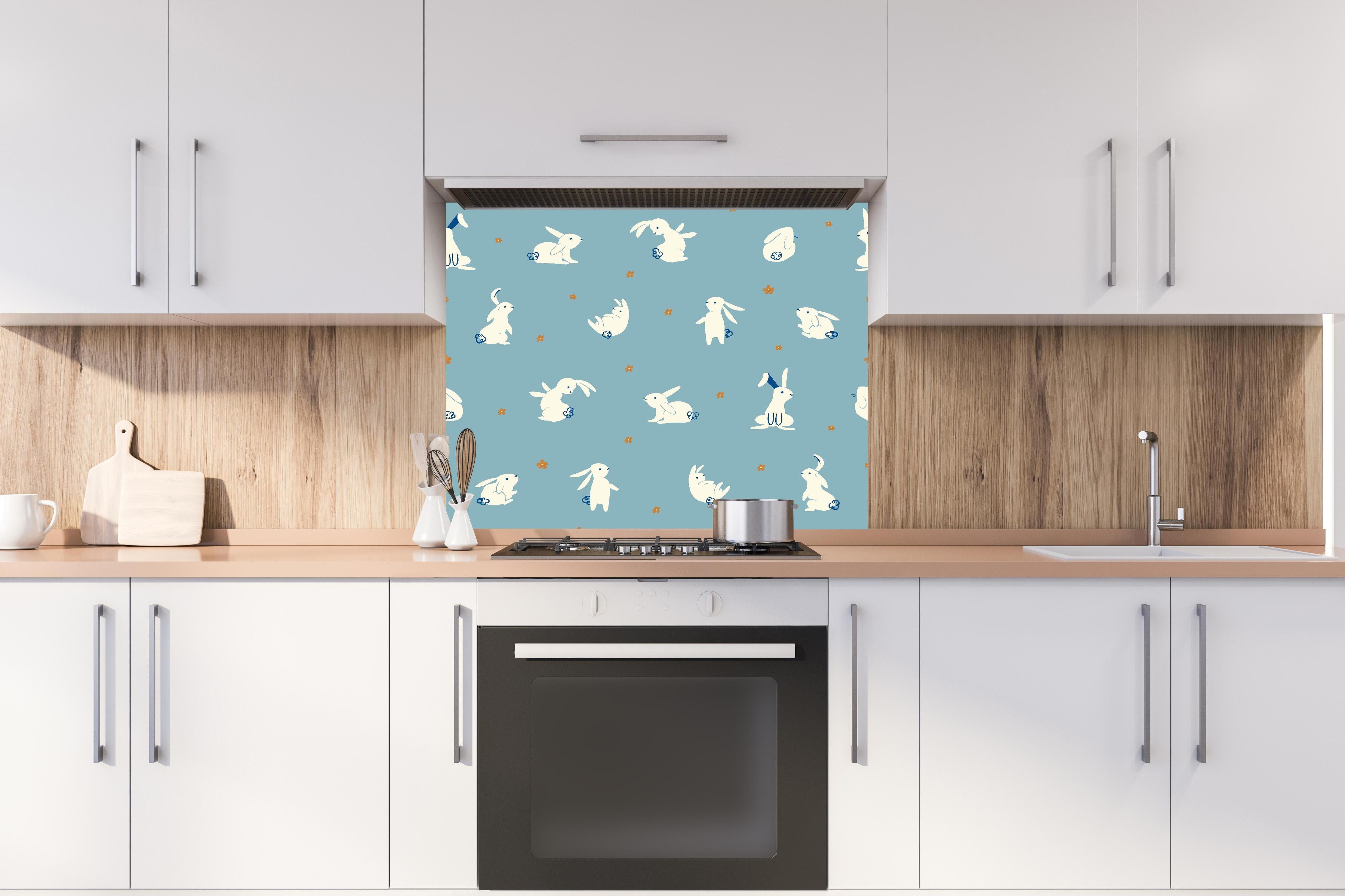 Spritzschutz - Süße Häschen auf Blau - Kinderstoffdesign hinter einem Cerankochfeld zwischen Holz-Kochutensilien