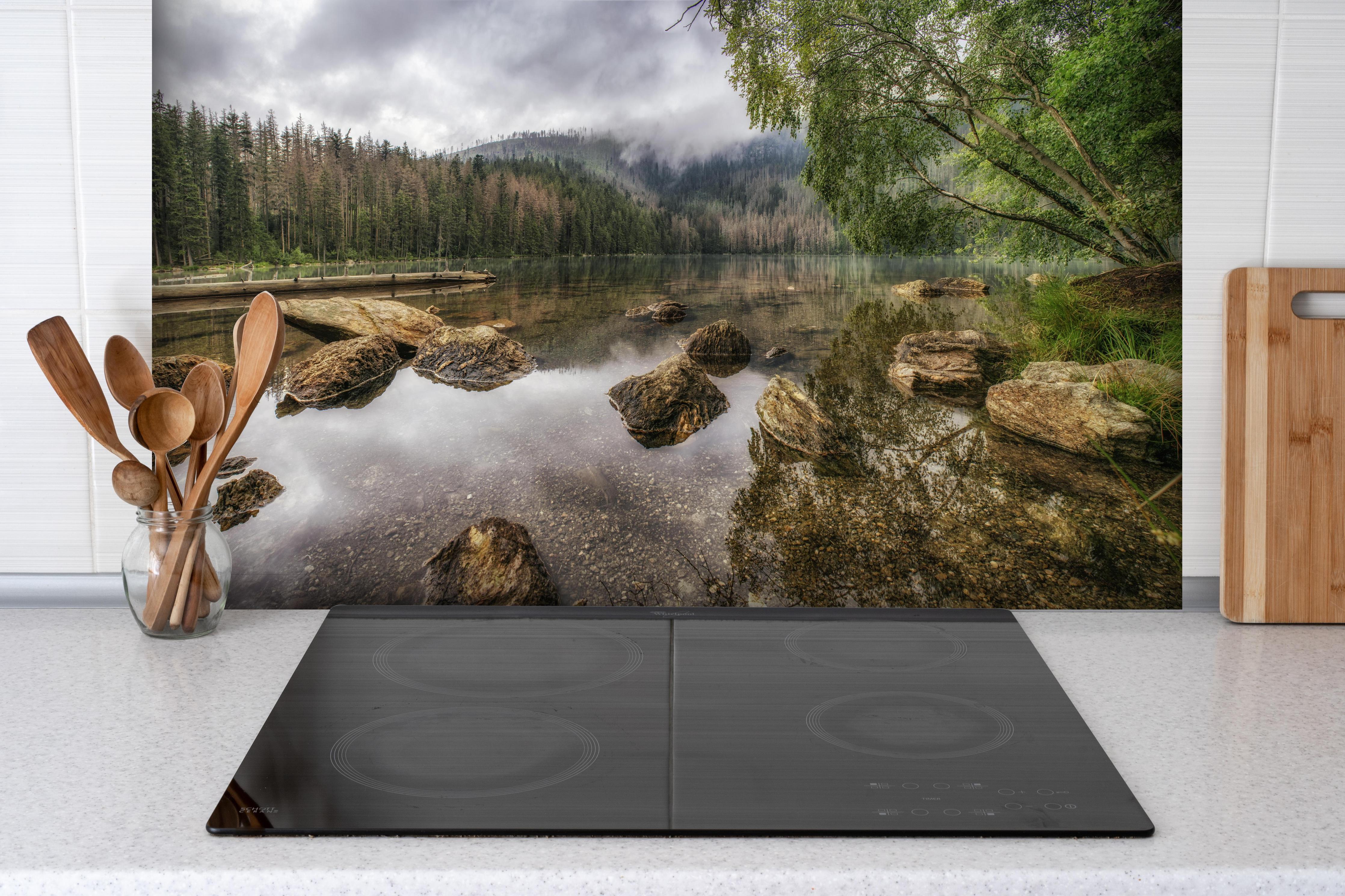 Spritzschutz - Sumava - Schwarzer See - Tschechische Republik hinter einem Cerankochfeld zwischen Holz-Kochutensilien