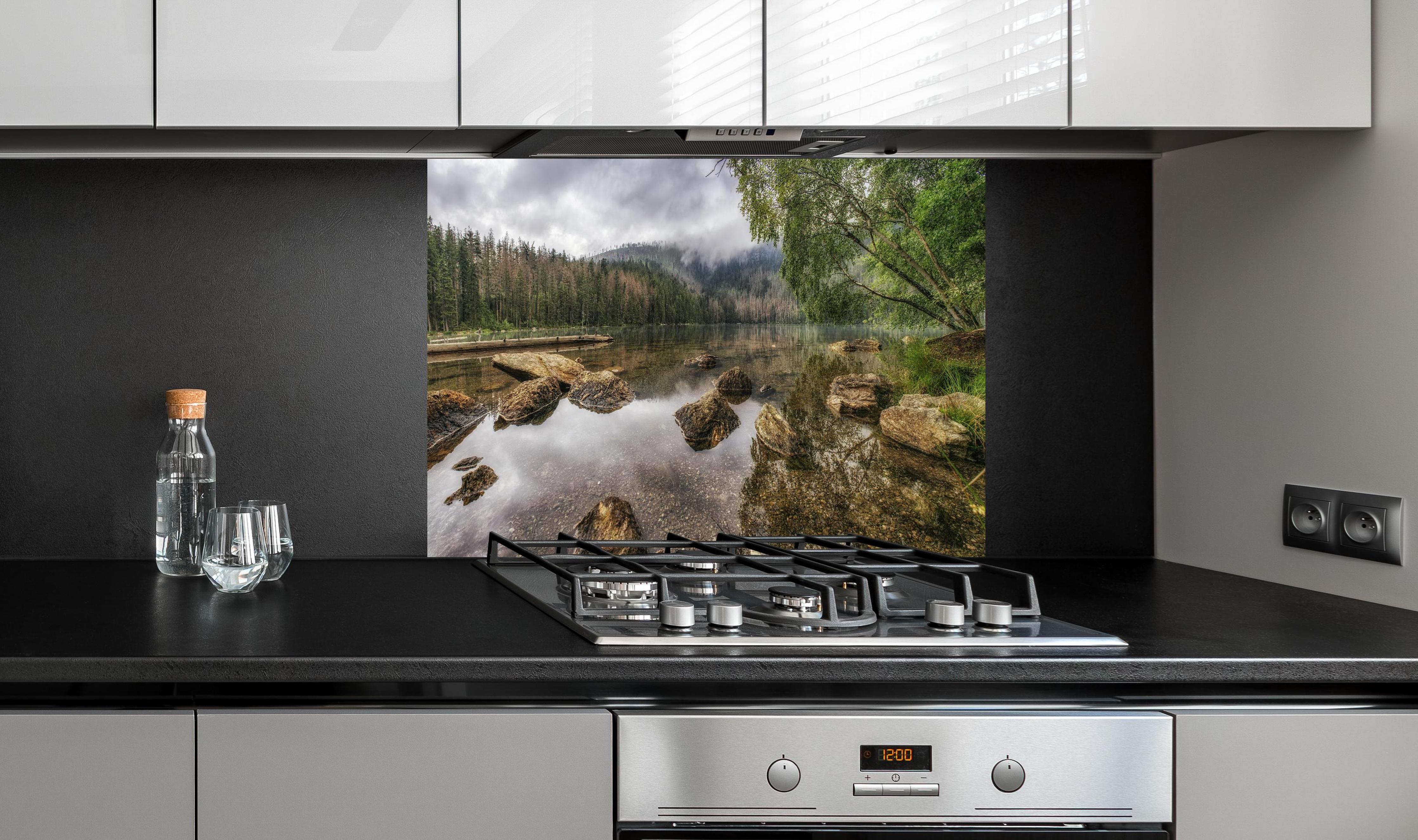 Spritzschutz - Sumava - Schwarzer See - Tschechische Republik hinter einem Cerankochfeld zwischen Holz-Kochutensilien