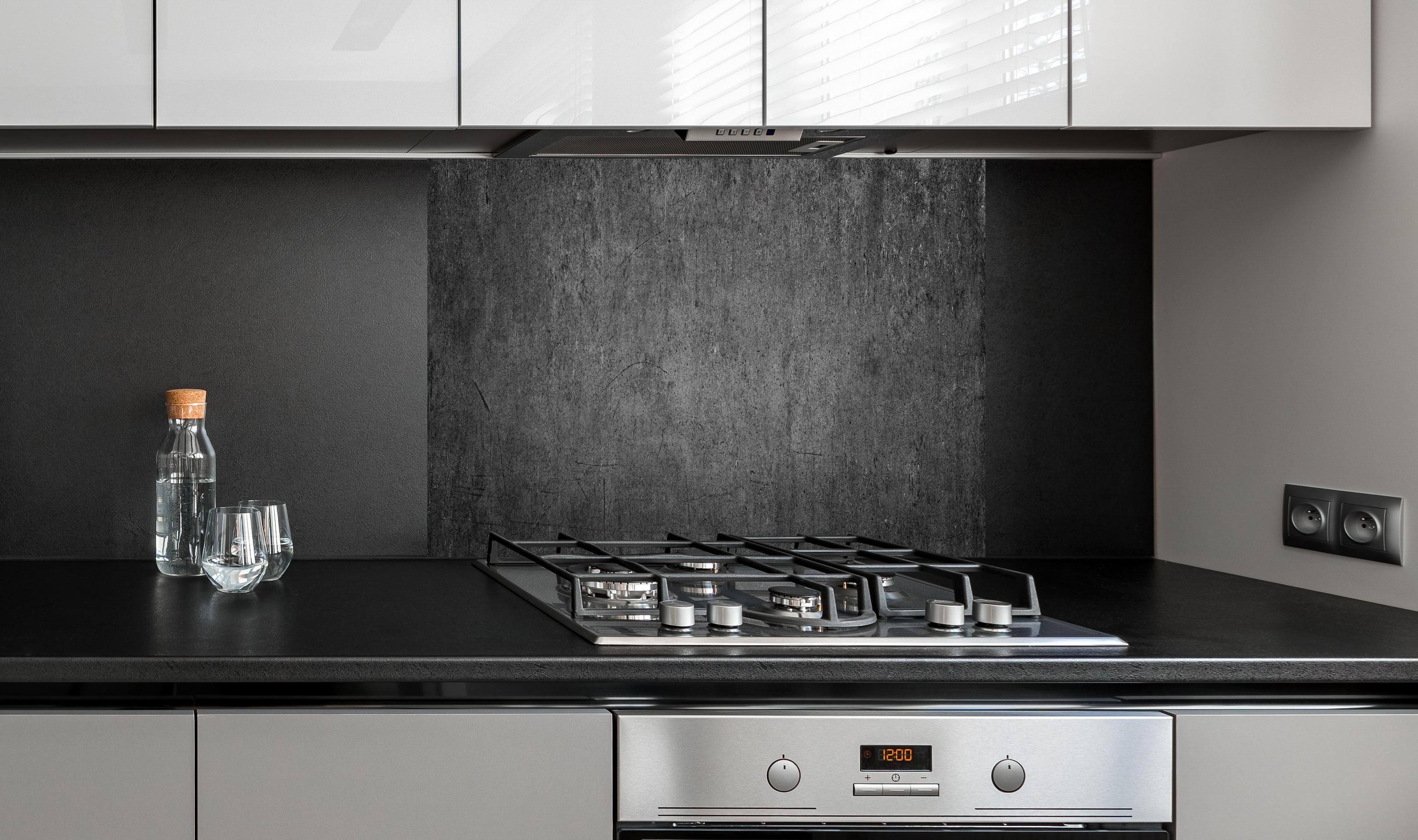 Spritzschutz - Textur Grauer Beton mit Schwarzen Nuancen hinter einem Cerankochfeld zwischen Holz-Kochutensilien