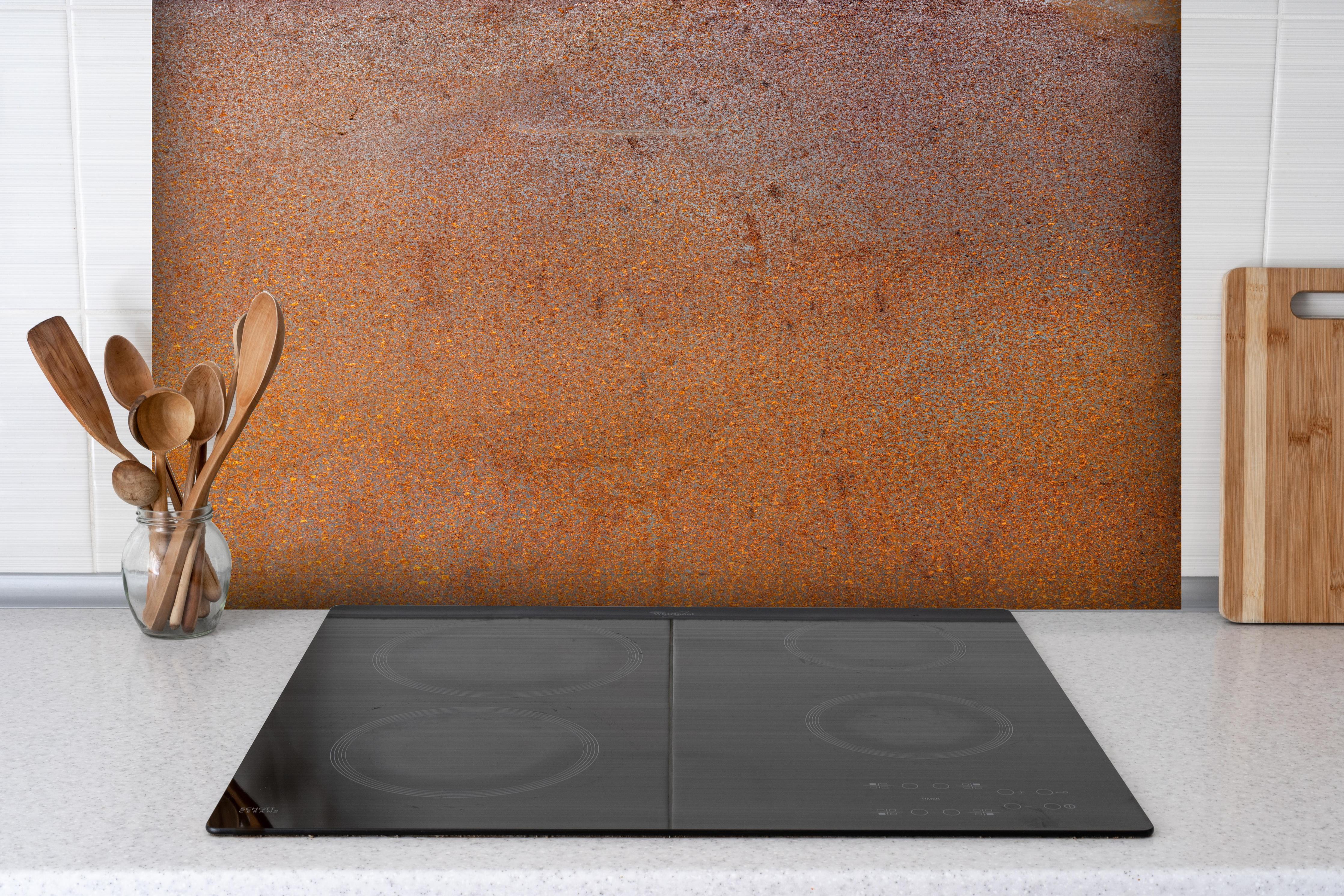 Spritzschutz - Textur von rostigem, bemaltem Stahl hinter einem Cerankochfeld zwischen Holz-Kochutensilien