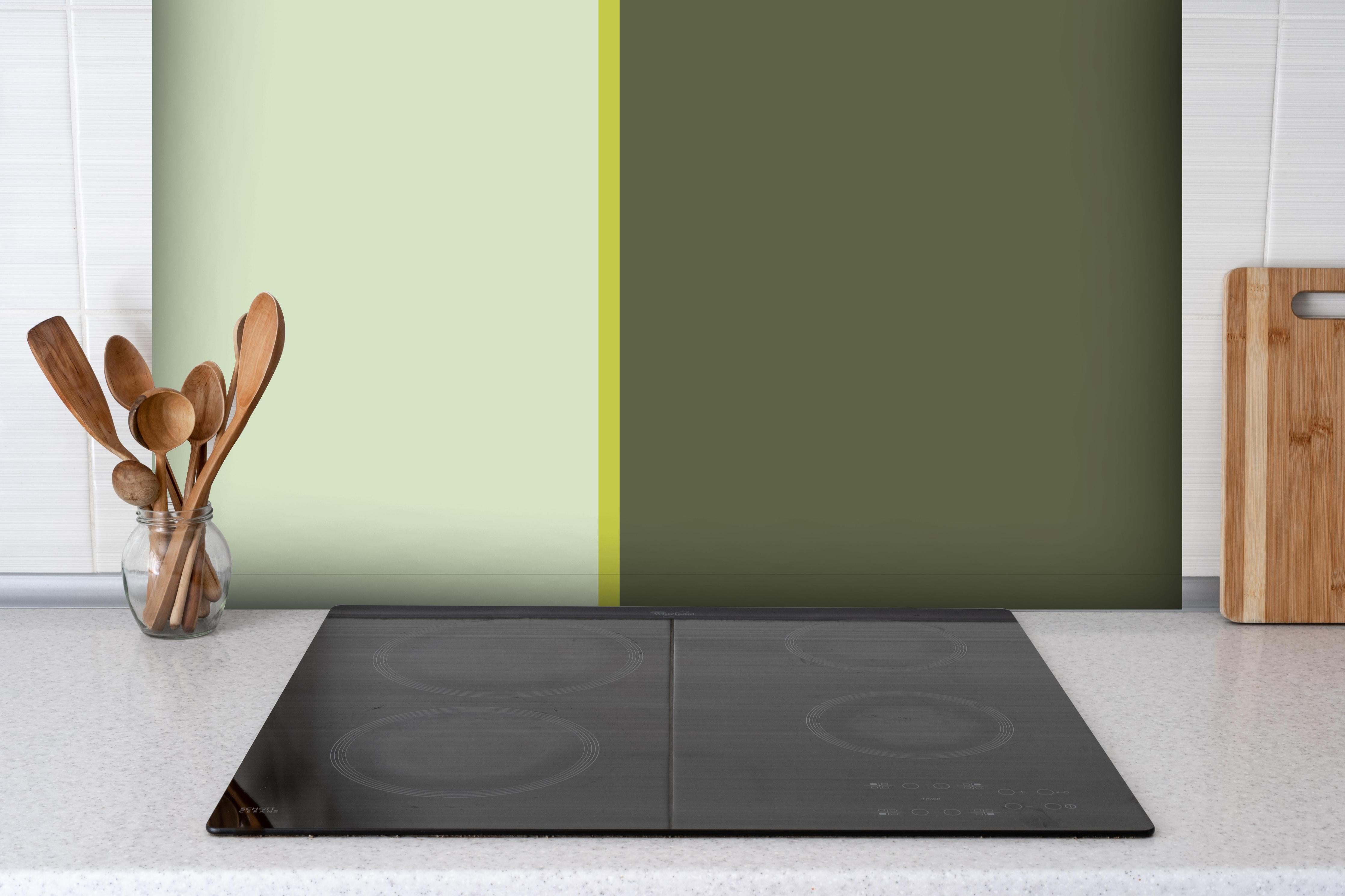Spritzschutz - The Greens - Easy Vertical - Olive hinter einem Cerankochfeld zwischen Holz-Kochutensilien