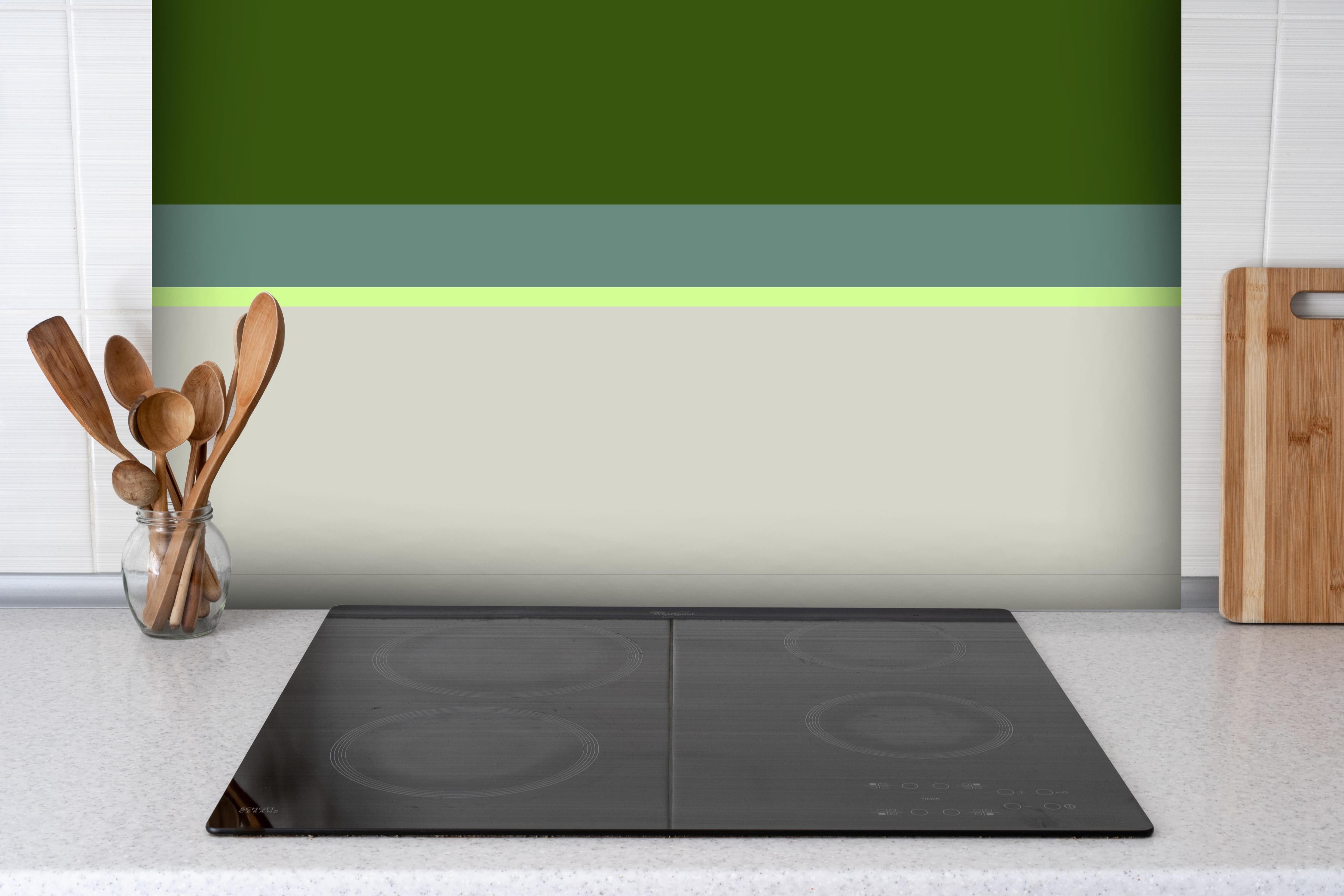 Spritzschutz - The Greens - Horizontal - Granny Smith hinter einem Cerankochfeld zwischen Holz-Kochutensilien