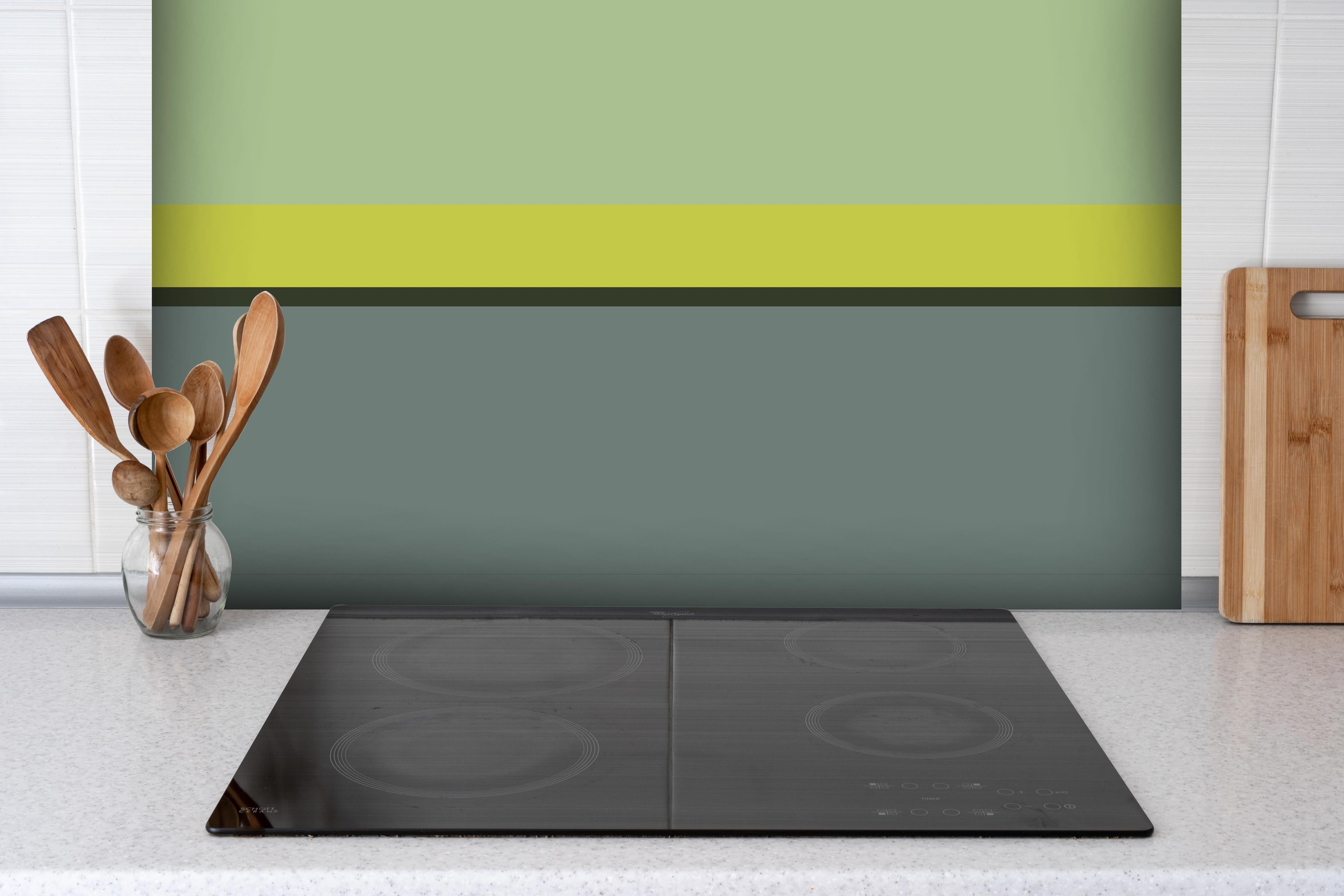 Spritzschutz - The Greens - Horizontal - Matcha hinter einem Cerankochfeld zwischen Holz-Kochutensilien