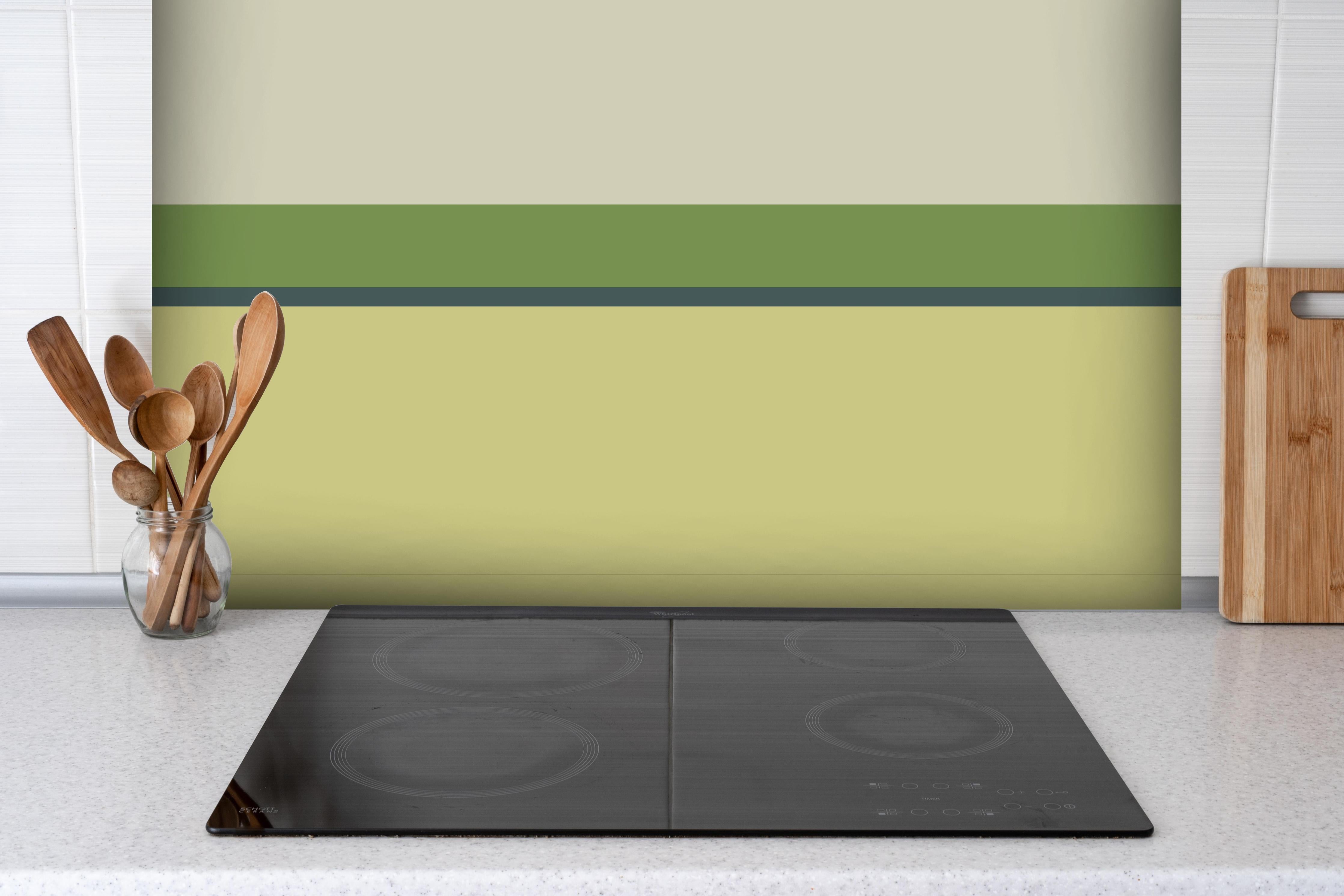 Spritzschutz - The Greens - Horizontal - Pistachio hinter einem Cerankochfeld zwischen Holz-Kochutensilien