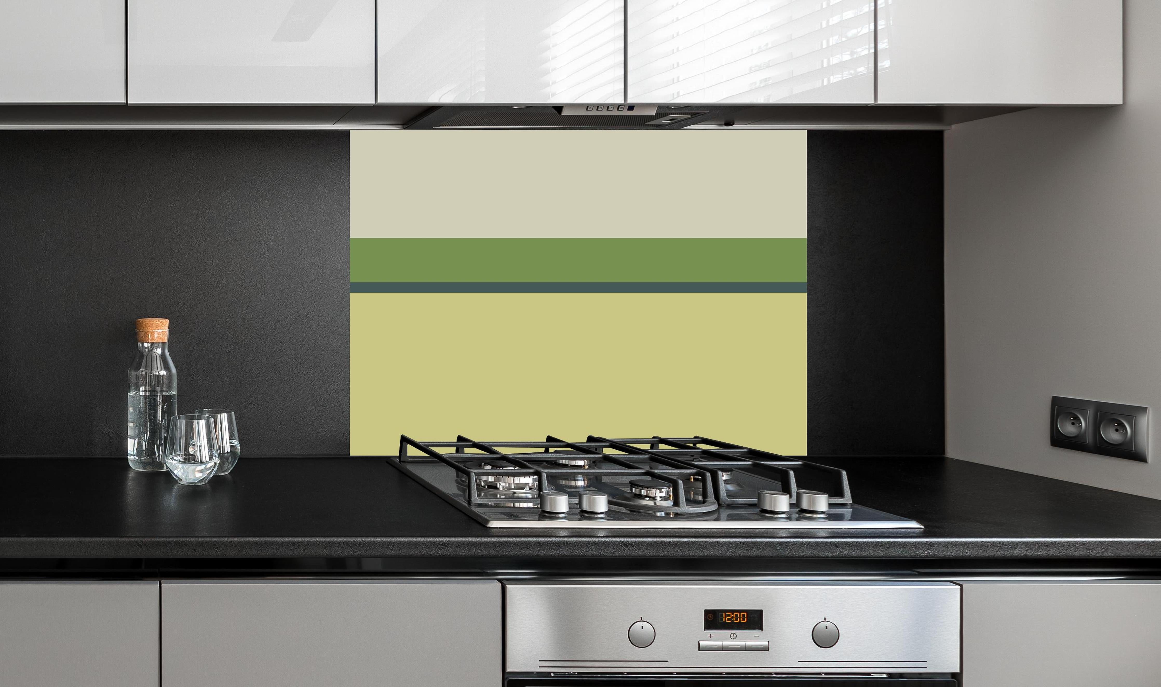 Spritzschutz - The Greens - Horizontal - Pistachio hinter einem Cerankochfeld zwischen Holz-Kochutensilien
