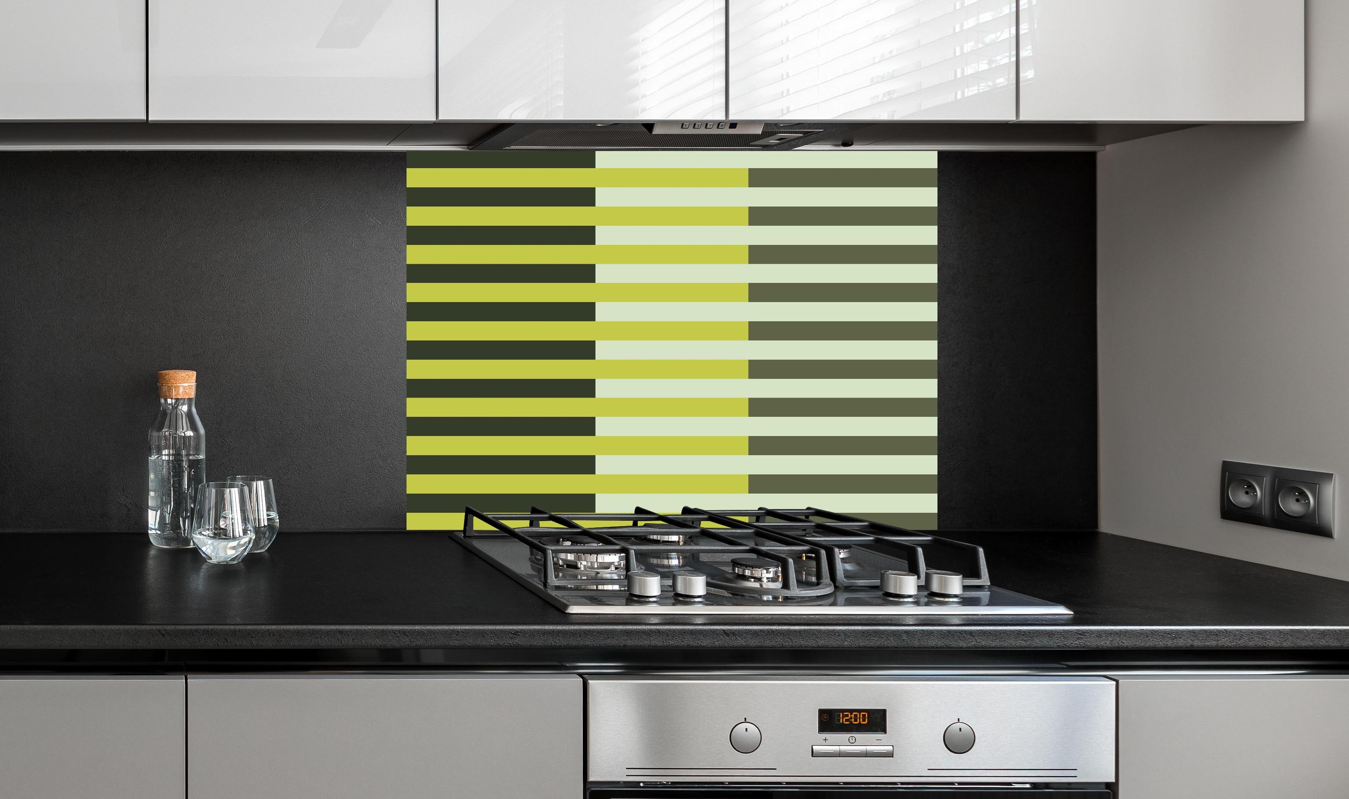 Spritzschutz - The Greens - Multy Stripes - Olive hinter einem Cerankochfeld zwischen Holz-Kochutensilien