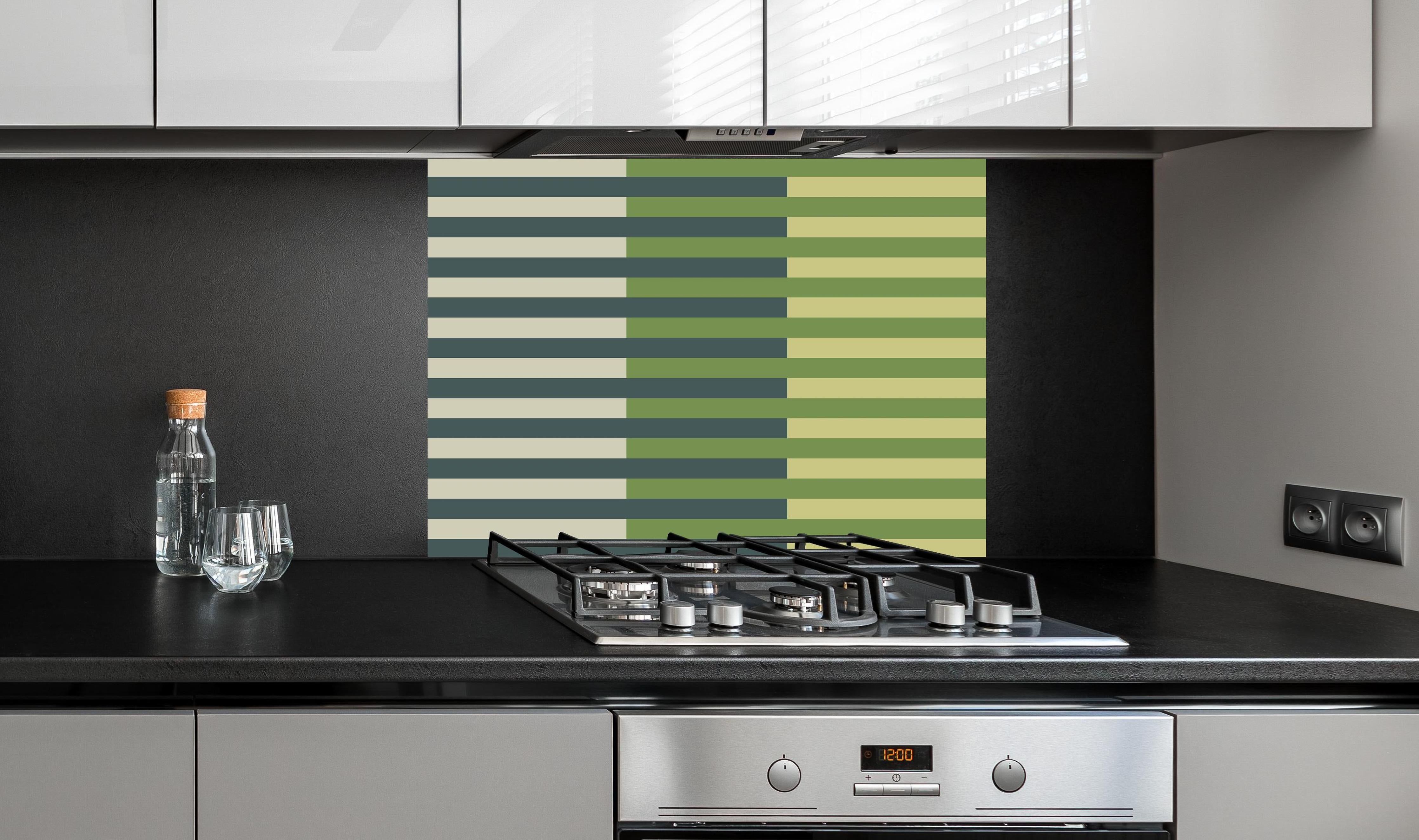 Spritzschutz - The Greens - Multy Stripes - Pistachio hinter einem Cerankochfeld zwischen Holz-Kochutensilien