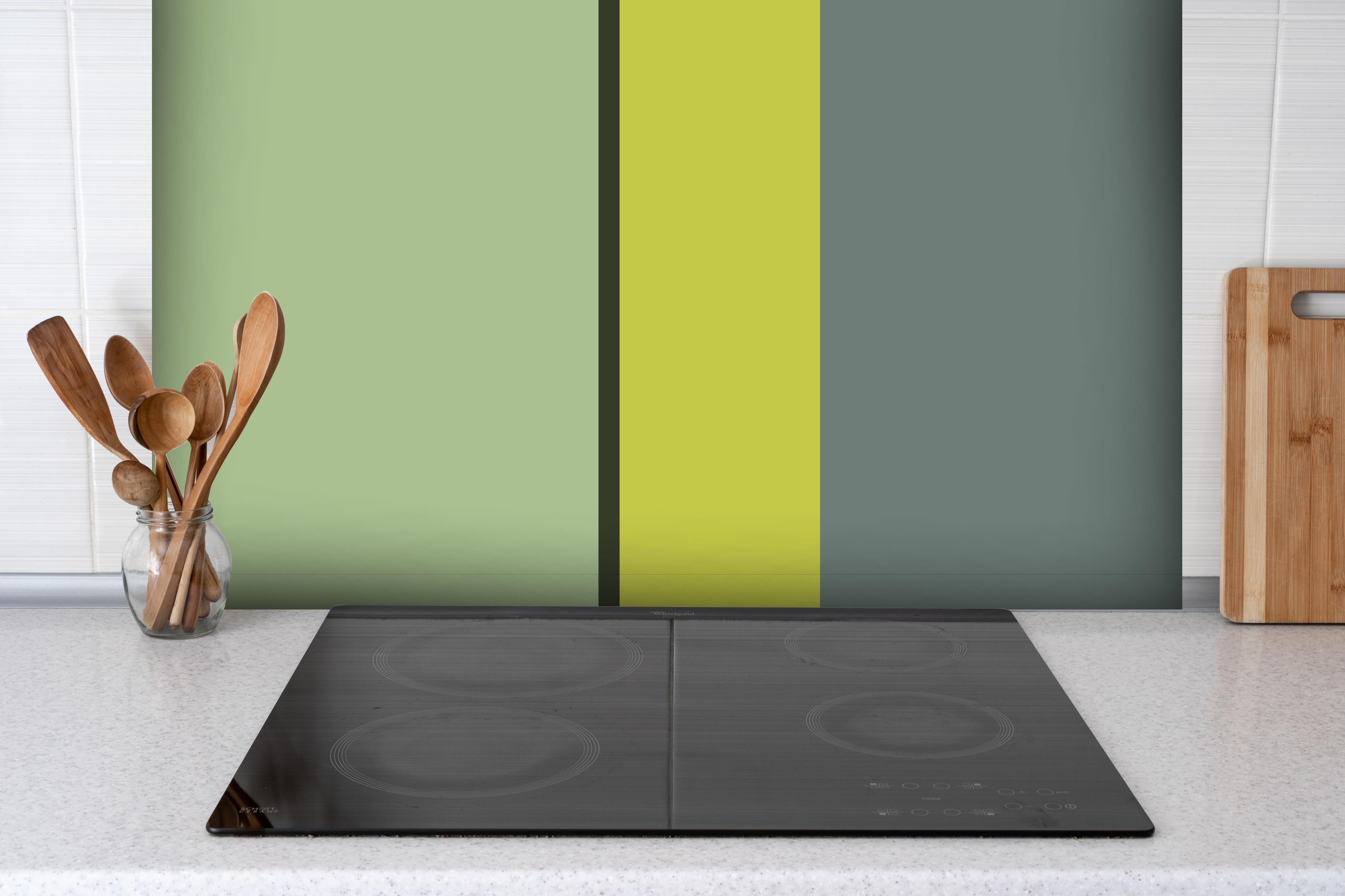 Spritzschutz - The Greens - Vertical - Matcha hinter einem Cerankochfeld zwischen Holz-Kochutensilien