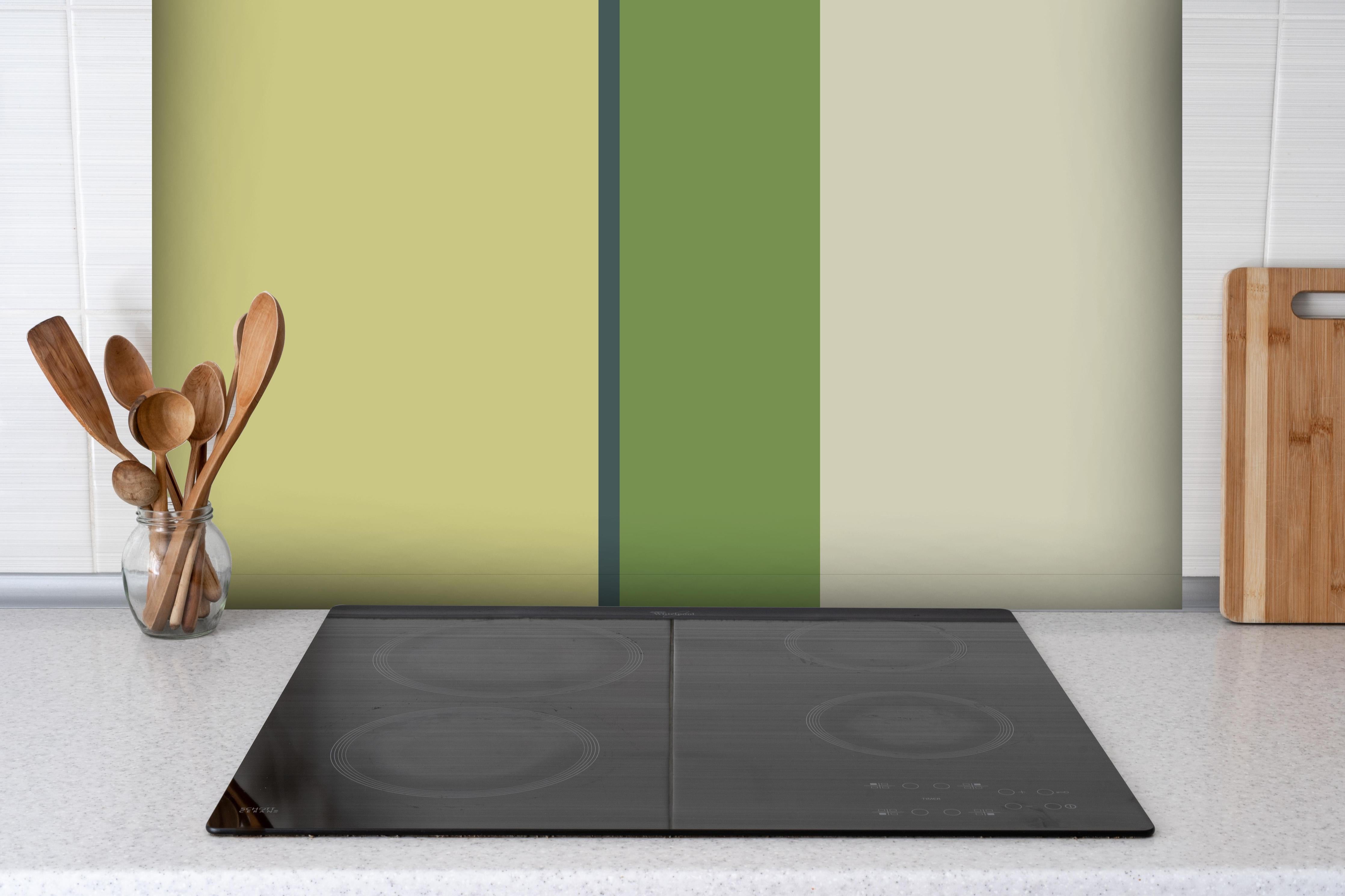 Spritzschutz - The Greens - Vertical - Pistachio hinter einem Cerankochfeld zwischen Holz-Kochutensilien