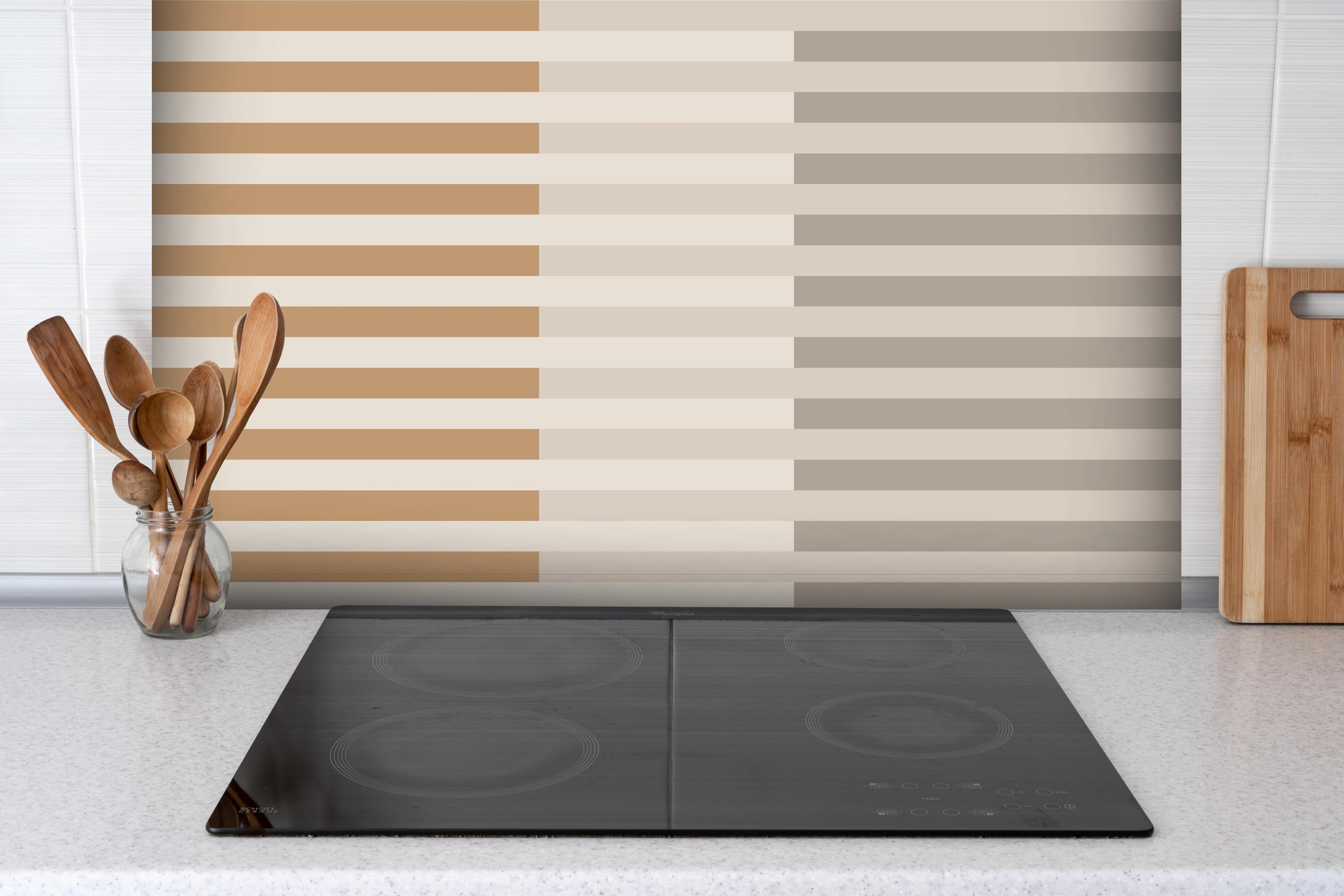 Spritzschutz - The Nudes - Multy Stripes - Caramel hinter einem Cerankochfeld zwischen Holz-Kochutensilien