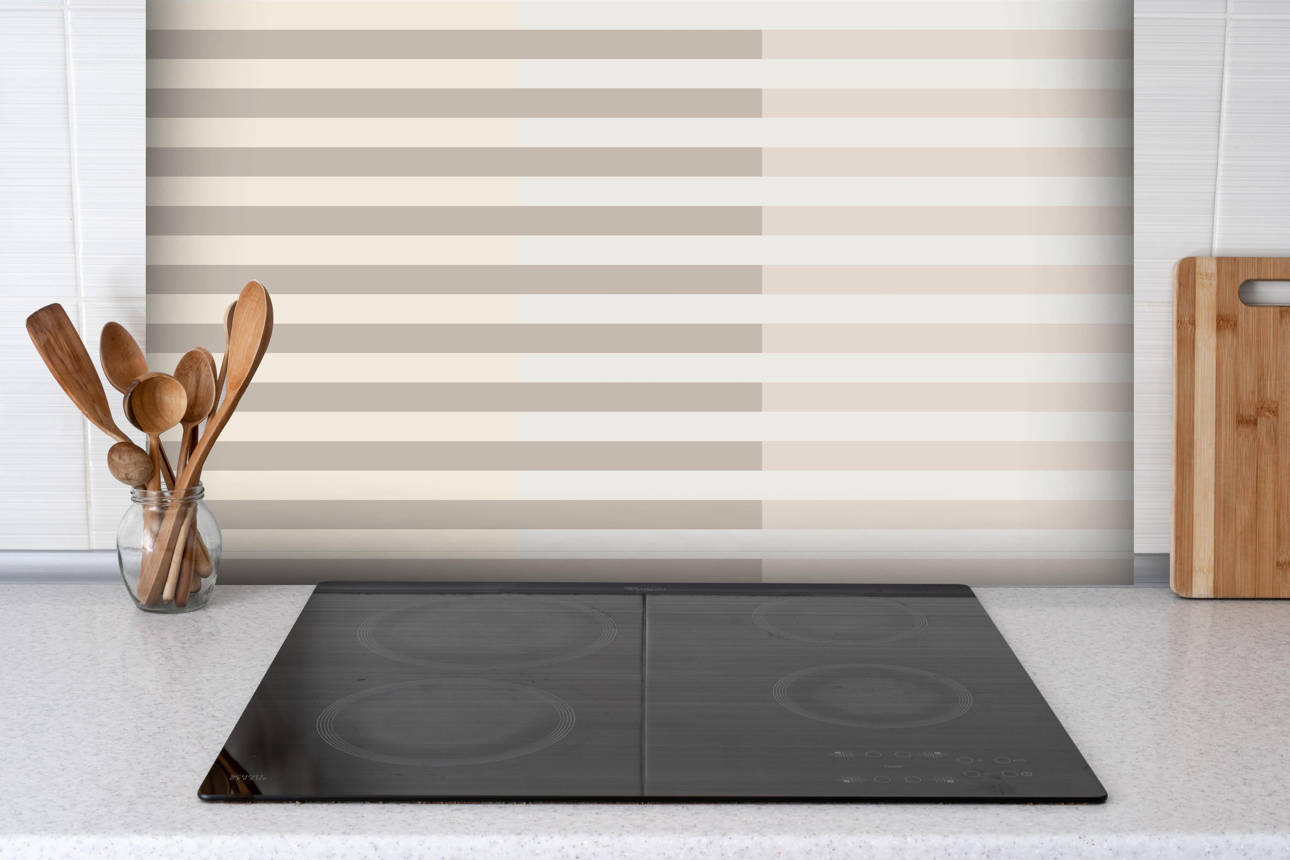 Spritzschutz - The Nudes - Multy Stripes - Latte hinter einem Cerankochfeld zwischen Holz-Kochutensilien