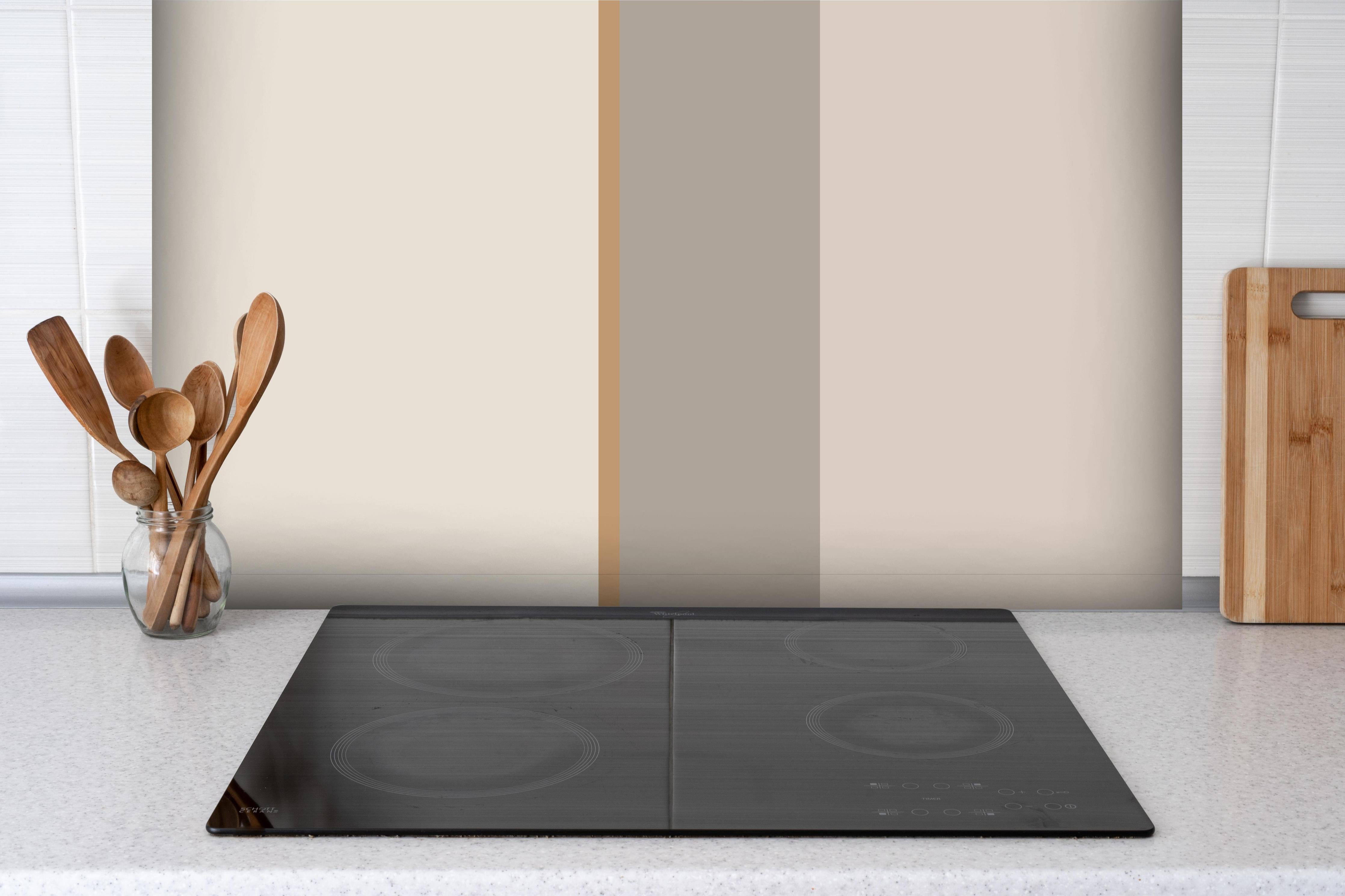 Spritzschutz - The Nudes - Vertikal - Caramel hinter einem Cerankochfeld zwischen Holz-Kochutensilien